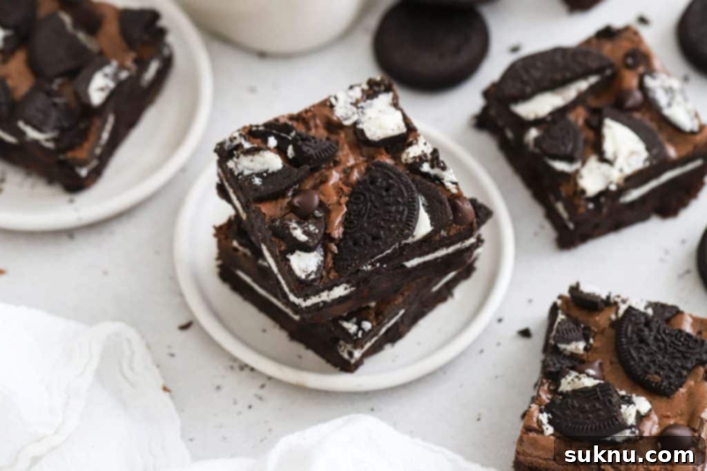 Stacked fudgy gluten-free Oreo brownies on a white plate, showing the cookie chunks.