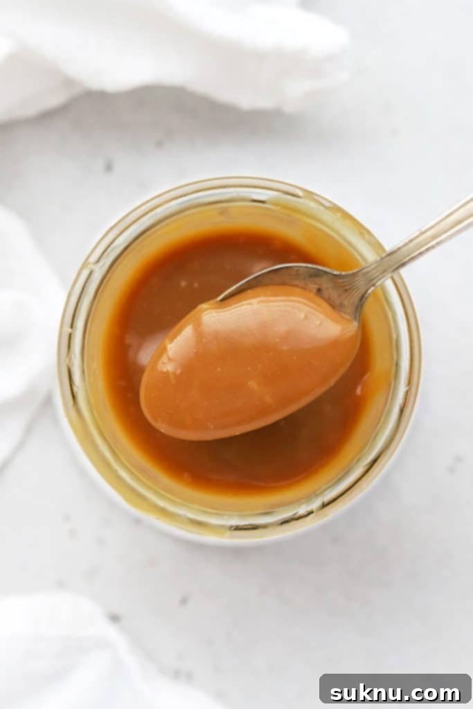 Scooping a spoonful of rich, golden easy caramel sauce, ready for dessert.