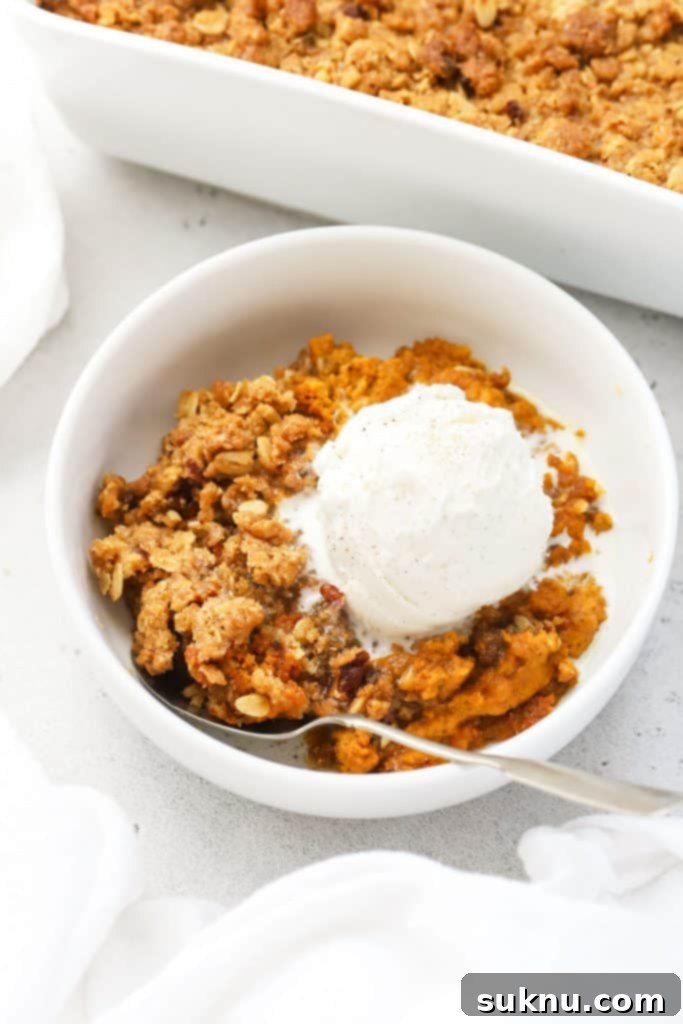 a bowl of gluten-free pumpkin crisp, topped with vanilla ice cream