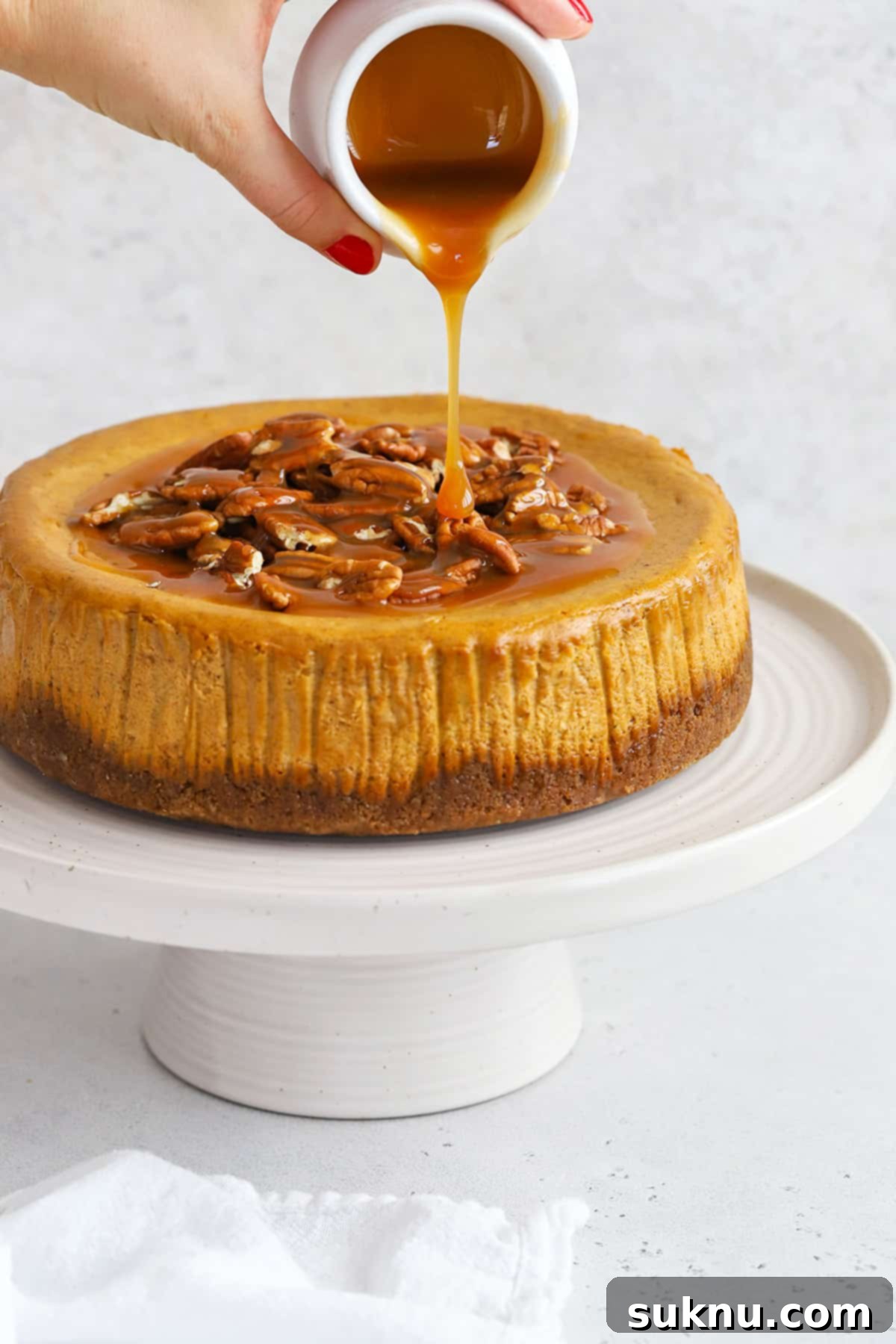 front view of gluten-free pumpkin cheesecake with pecans and caramel sauce