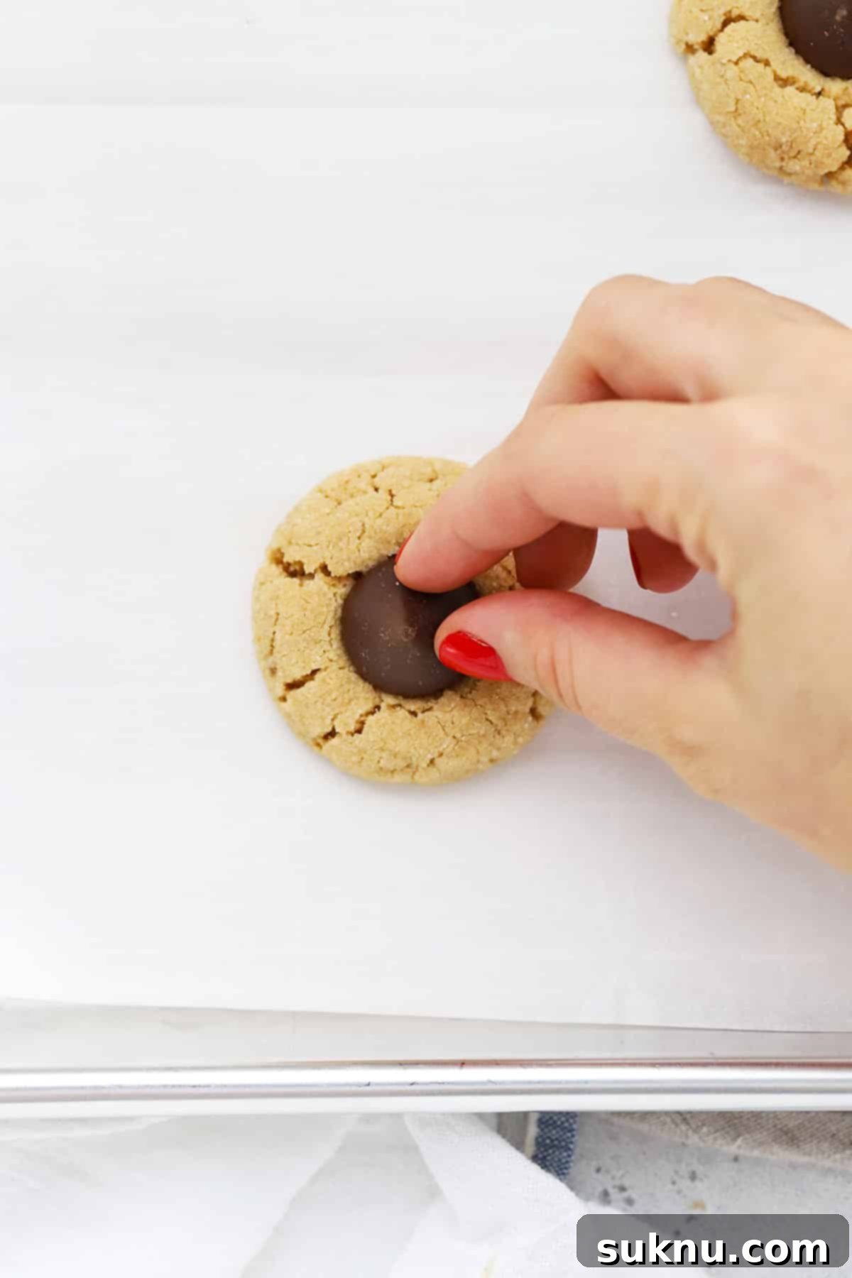 adding a Hershey's kiss to the center of a small peanut butter cookie to make gluten-free peanut butter blossom cookies
