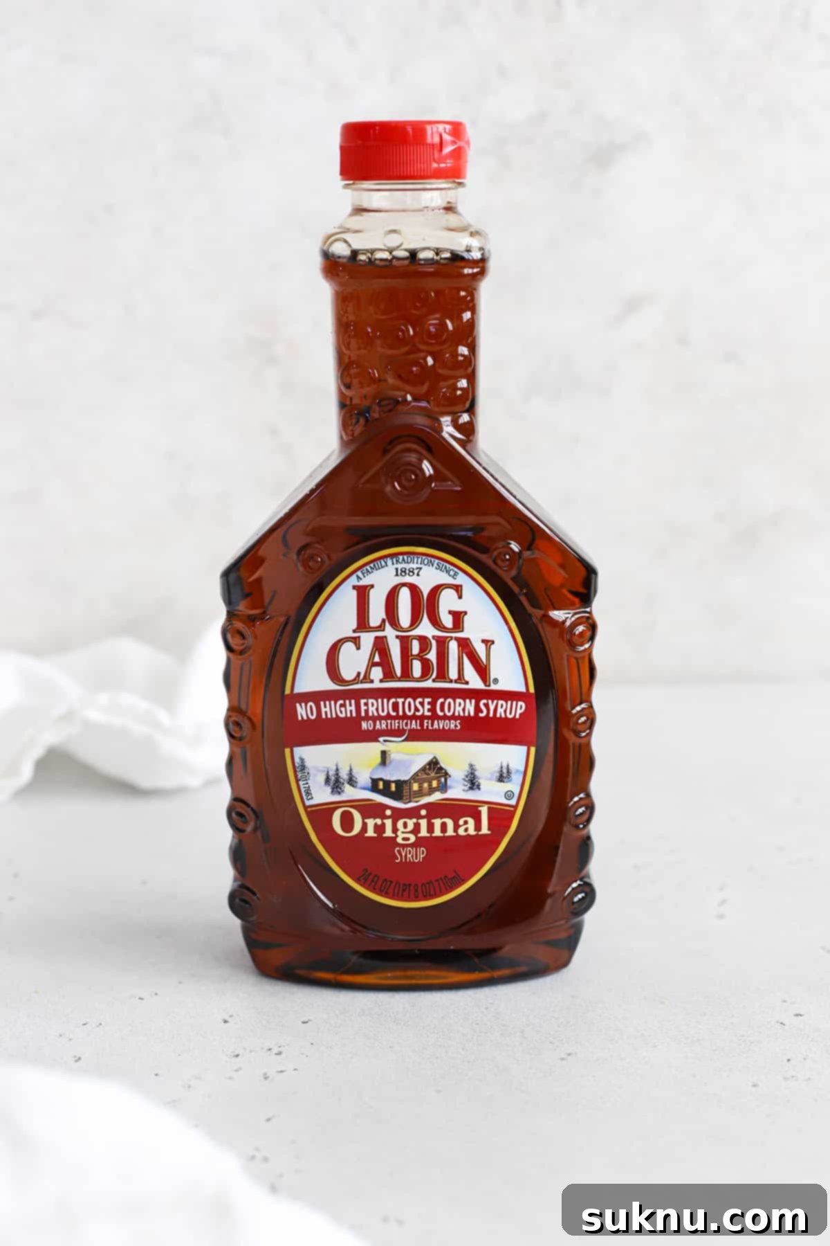 The Gluten-Free Verdict On Maple Syrup 7 Front view of a bottle of Log Cabin pancake syrup on a white background, confirming its gluten-free status.