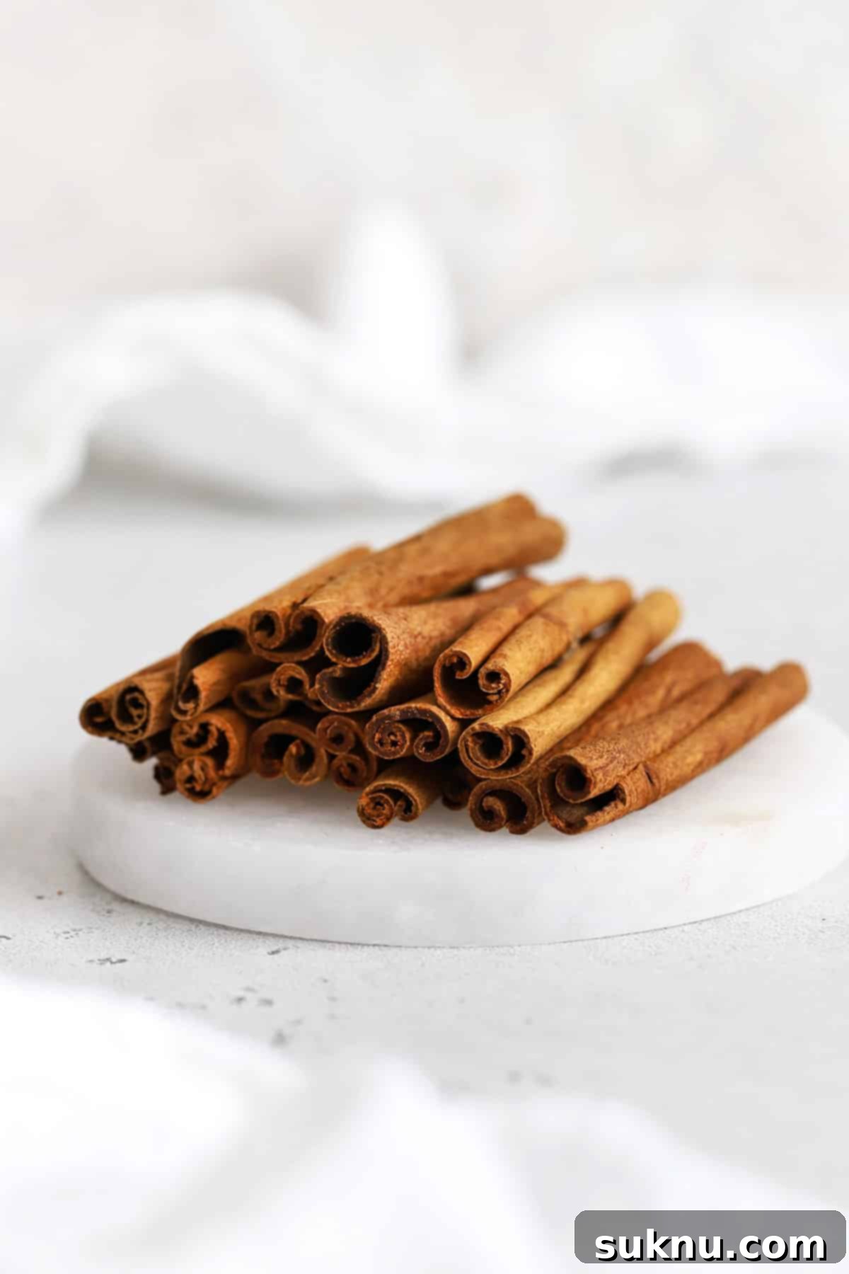 Front view of a stack of cinnamon sticks on a white coaster