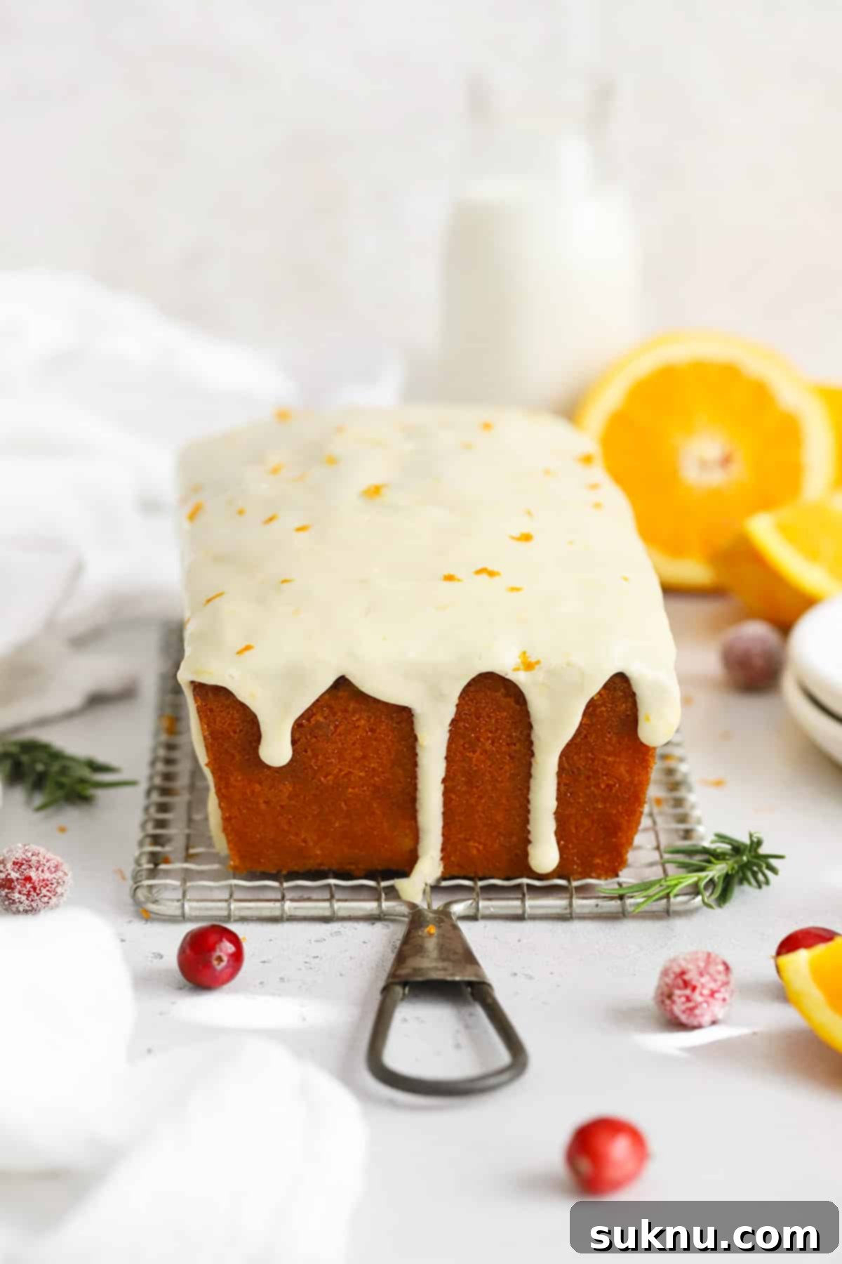 Front view of gluten-free cranberry orange loaf cake with orange glaze dripping down the sides