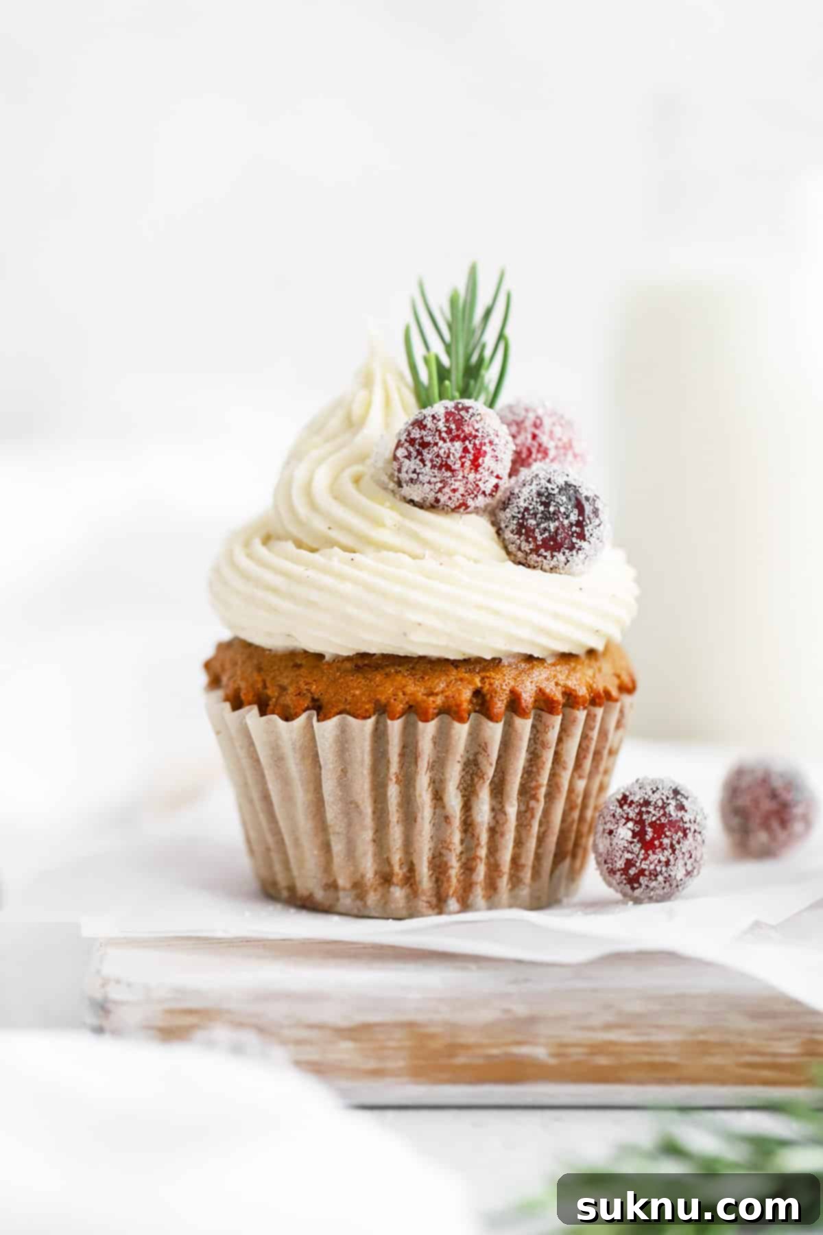 Sparkling Sugared Cranberries 11 Front view of a gluten-free gingerbread cupcake topped with cream cheese, sugared cranberries, and rosemary