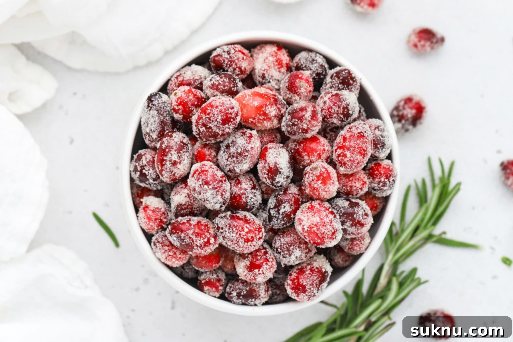 Sparkling Sugared Cranberries 21 Overhead view of a bowl of sugared cranberries with a sprig of rosemary in the background