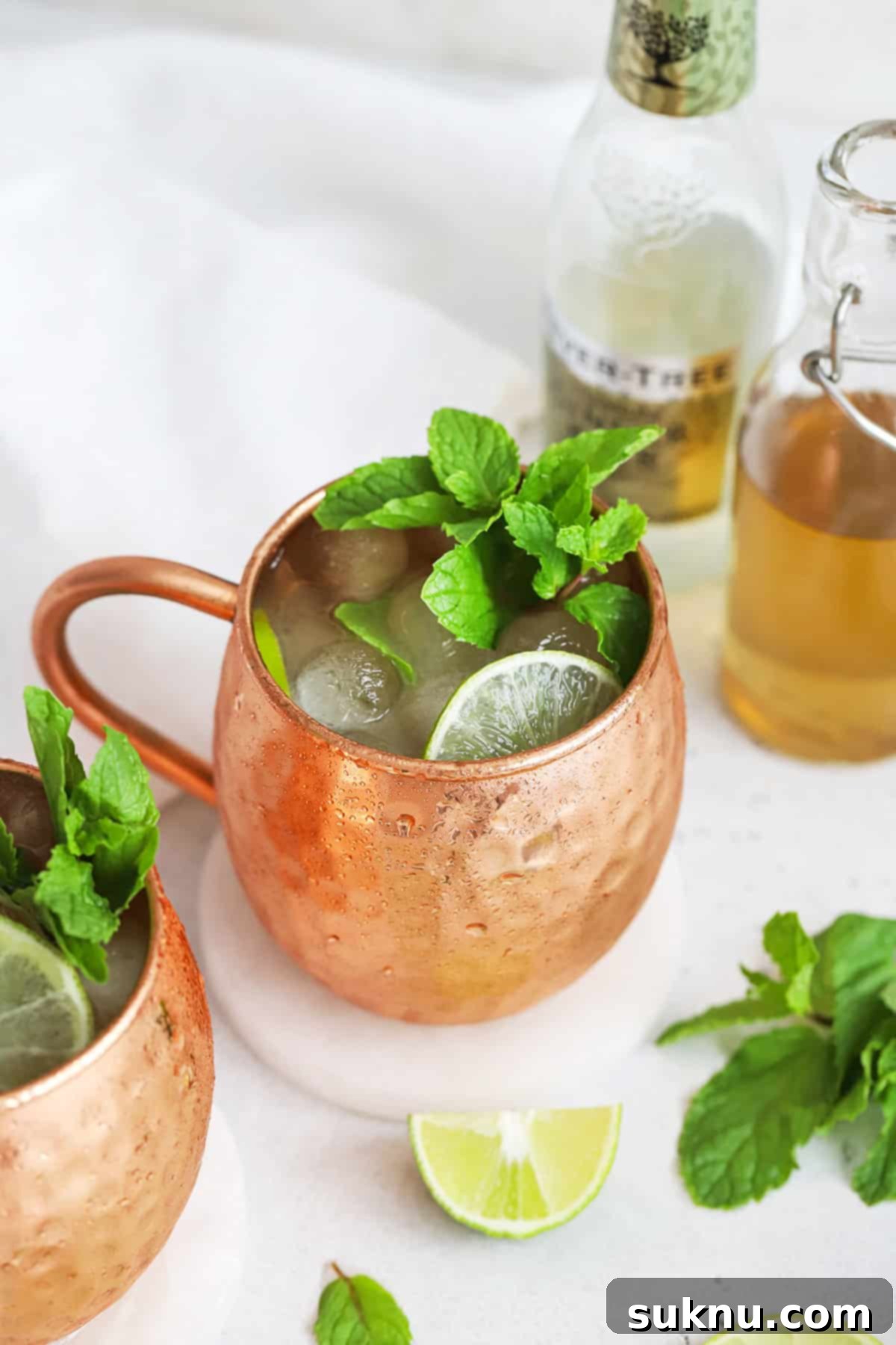 Front view of two non-alcoholic Moscow Mule mocktails in copper mugs, garnished with fresh mint and lime slices