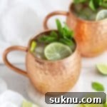 Front view of two non-alcoholic Moscow Mule mocktails in copper mugs with fresh mint and lime slices