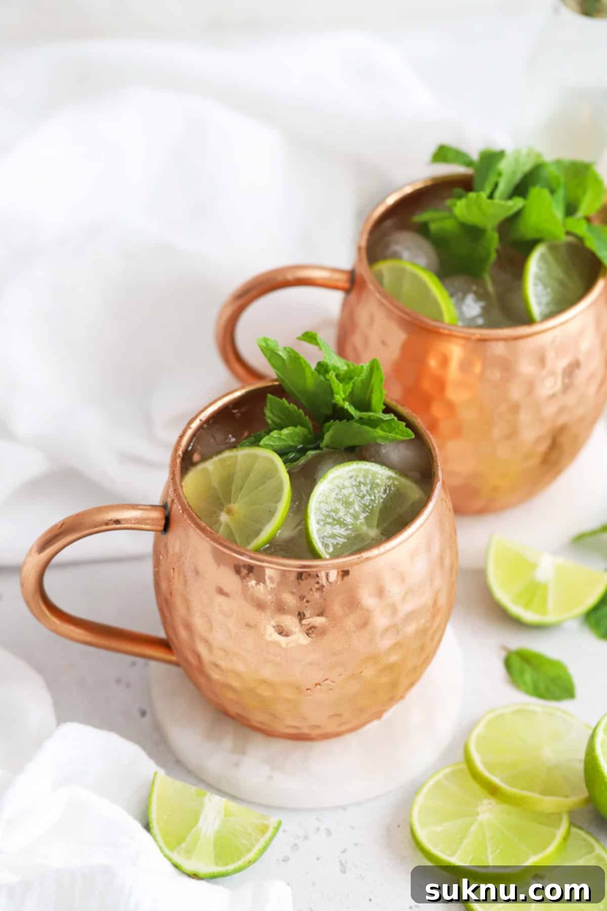 Front view of two non-alcoholic Moscow Mule mocktails in copper mugs with fresh mint and lime slices, ready to be enjoyed