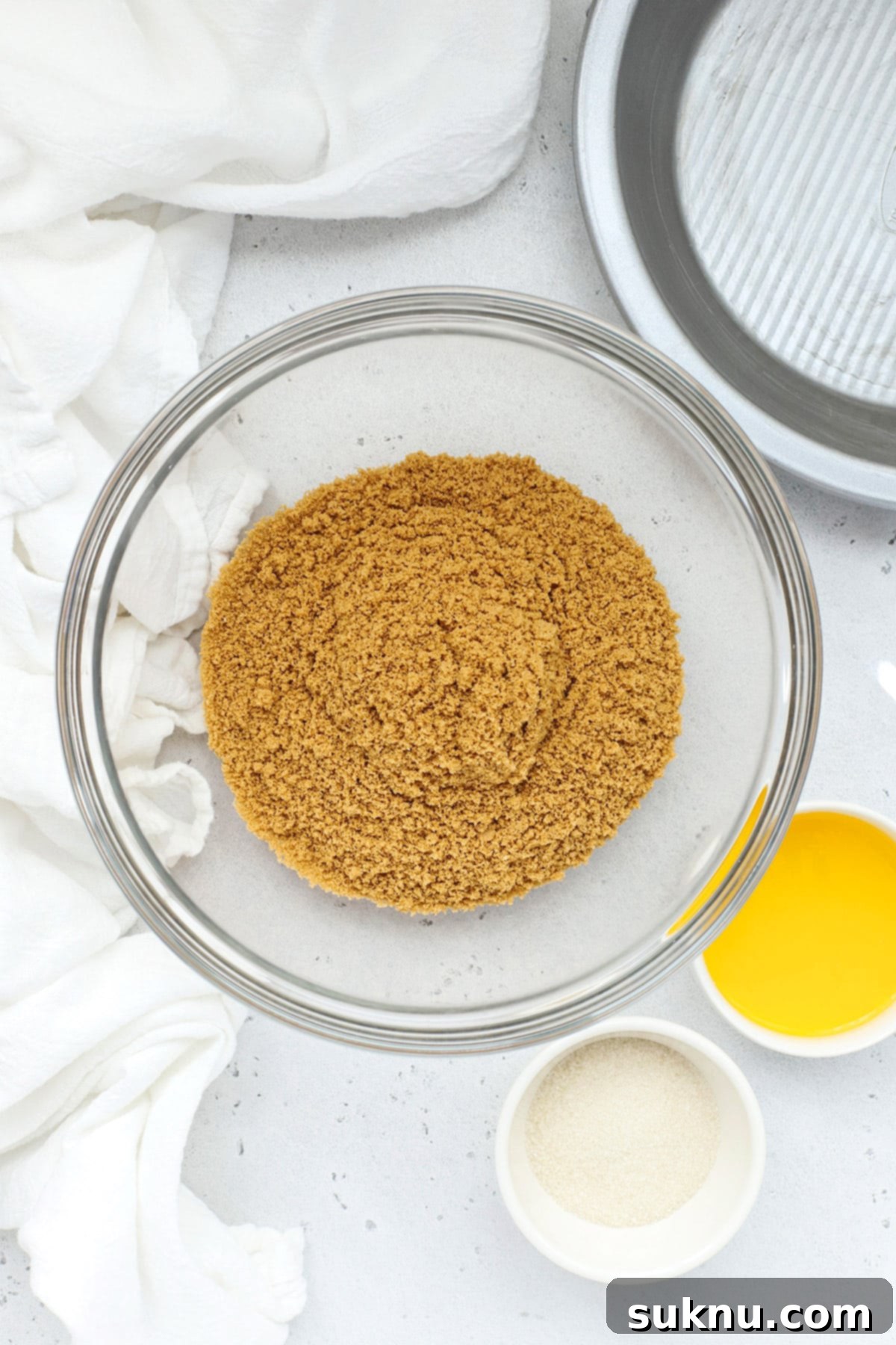 Overhead view of gluten-free graham crackers, sugar, and melted butter ingredients for pie crust