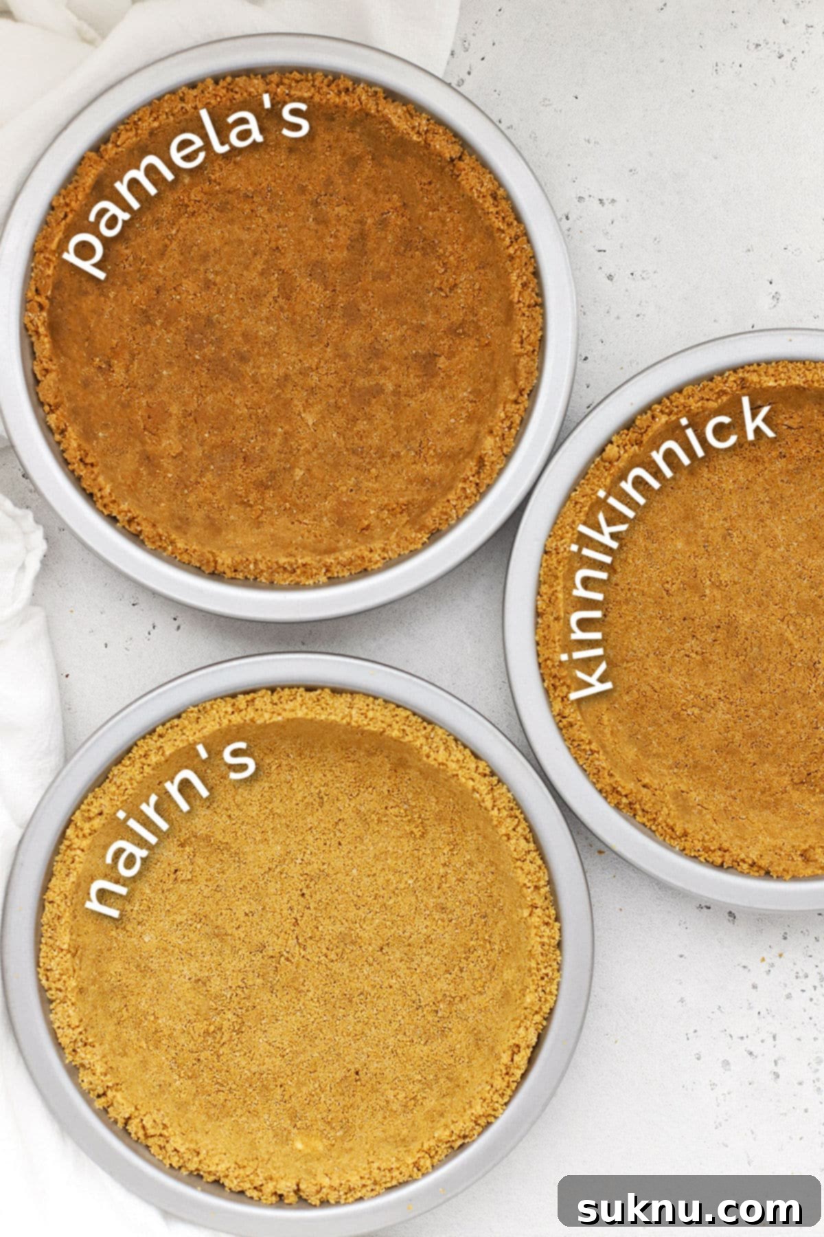 Three perfectly baked gluten-free graham cracker crusts in various metal pie pans