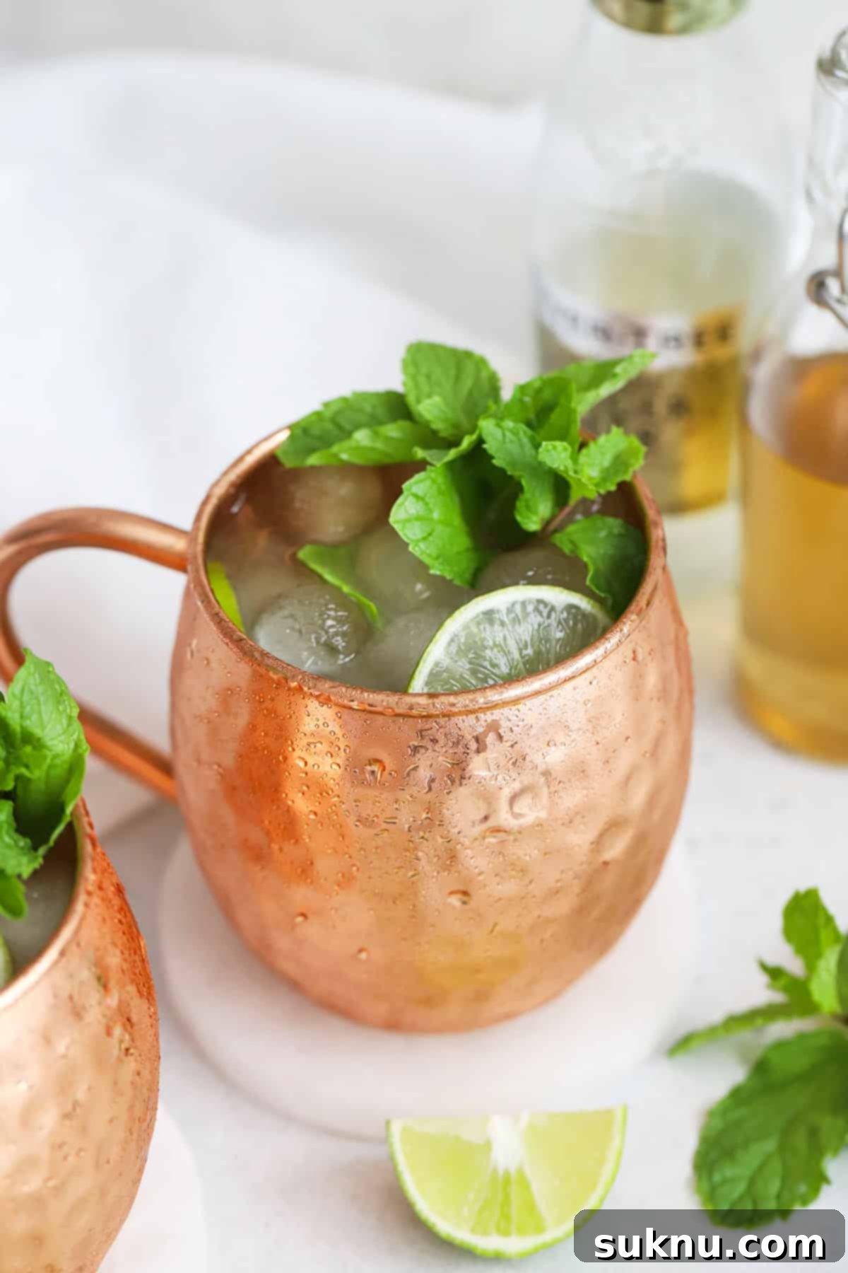 Front view of two non-alcoholic moscow mule mocktails in copper mugs with fresh mint and lime slices