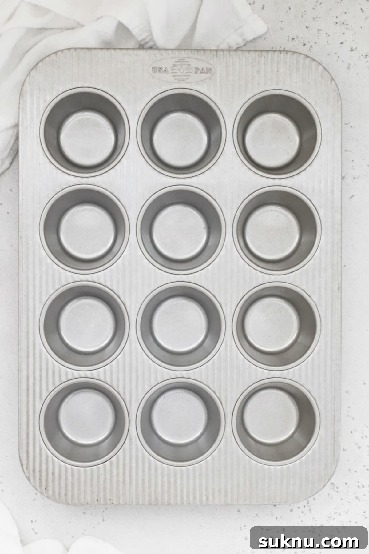 A sparkling clean, light-colored metal muffin and cupcake pan, ready for baking delicious treats.