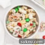 A white bowl of gluten-free christmas chex mix with m&ms and pretzels