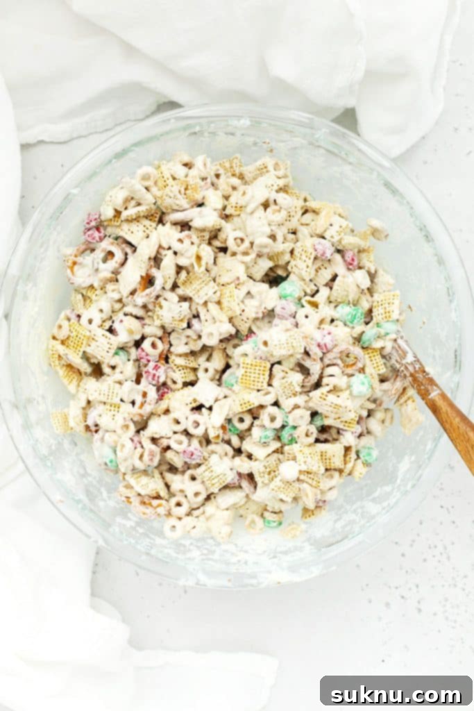 Stirring gluten-free Christmas chex mix to coat it in melted white chocolate