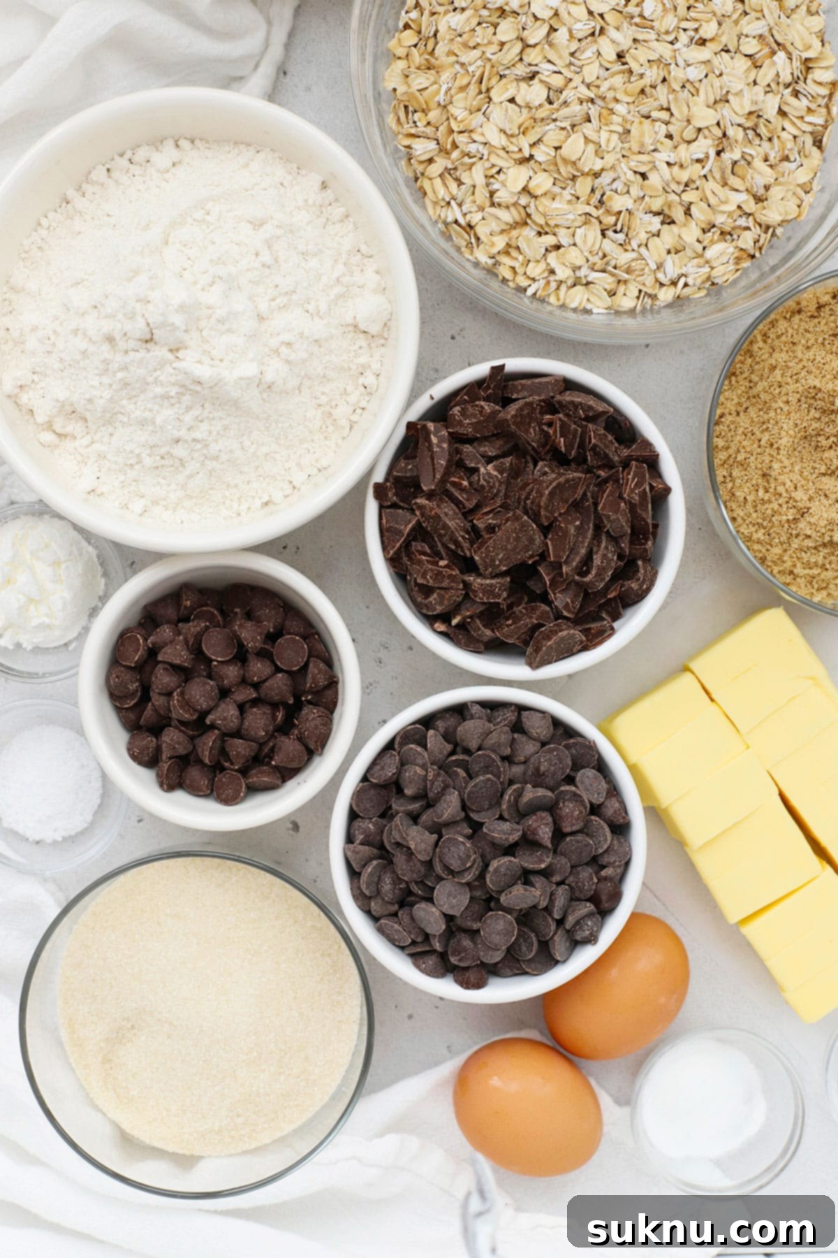 Various ingredients for gluten-free oatmeal chocolate chip cookies neatly arranged in small white bowls