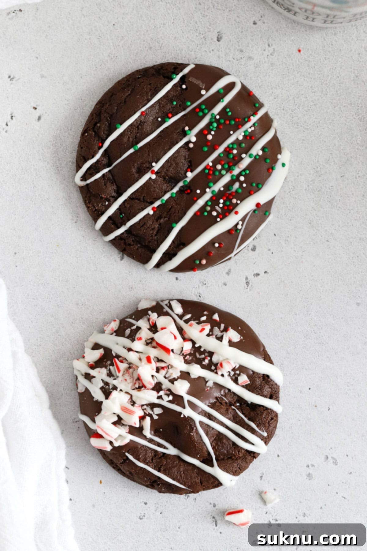 Finished gluten-free chocolate candy cane cookies on a white background, garnished with melted chocolate and crushed peppermint
