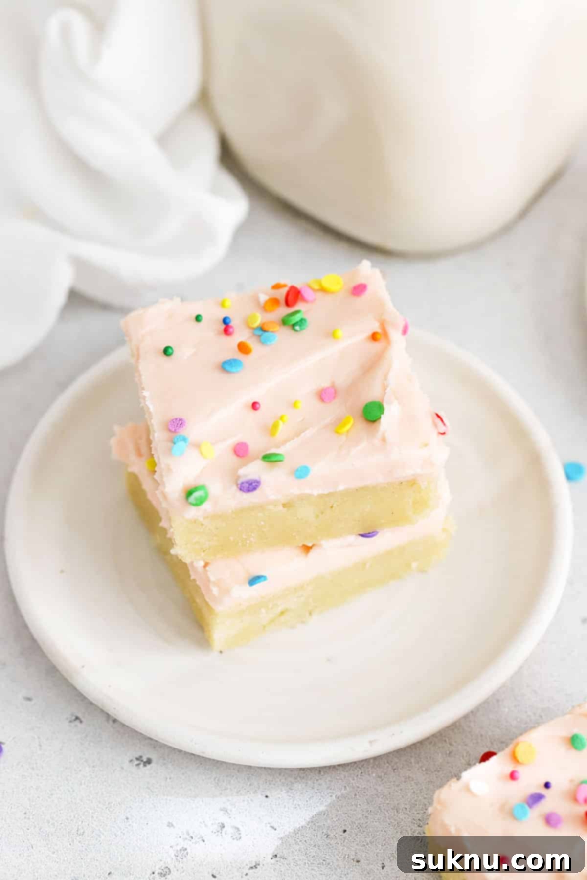 Perfect Gluten-Free Sugar Cookie Bars 7 Gluten-free sugar cookie bars with pink frosting and sprinkles, beautifully arranged on pristine white plates for a delightful display.