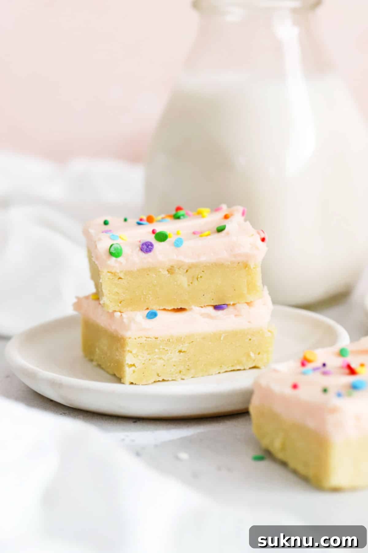 Perfect Gluten-Free Sugar Cookie Bars 8 Gluten-free sugar cookie bars with delicate pink frosting and a scattering of colorful sprinkles, thoughtfully arranged on white plates.