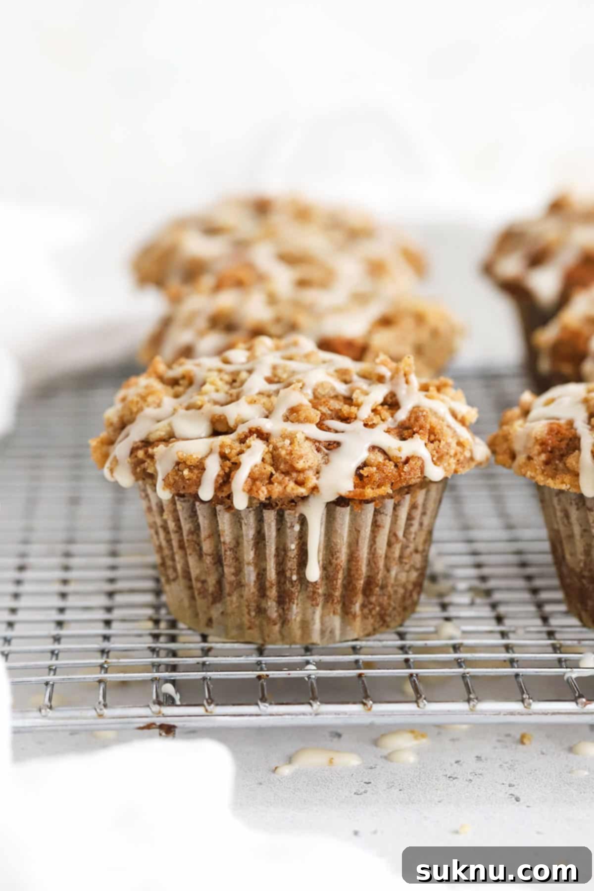 Gluten-Free Banana Crumb Muffin With cinnamon Streusel and maple glaze on a wire rack.