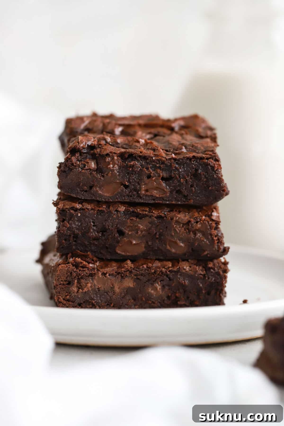 Decadent Fudgy Gluten-Free Vegan Brownies 2 three fudgy gluten-free vegan brownies stacked on a white plate with a glossy, crackly top