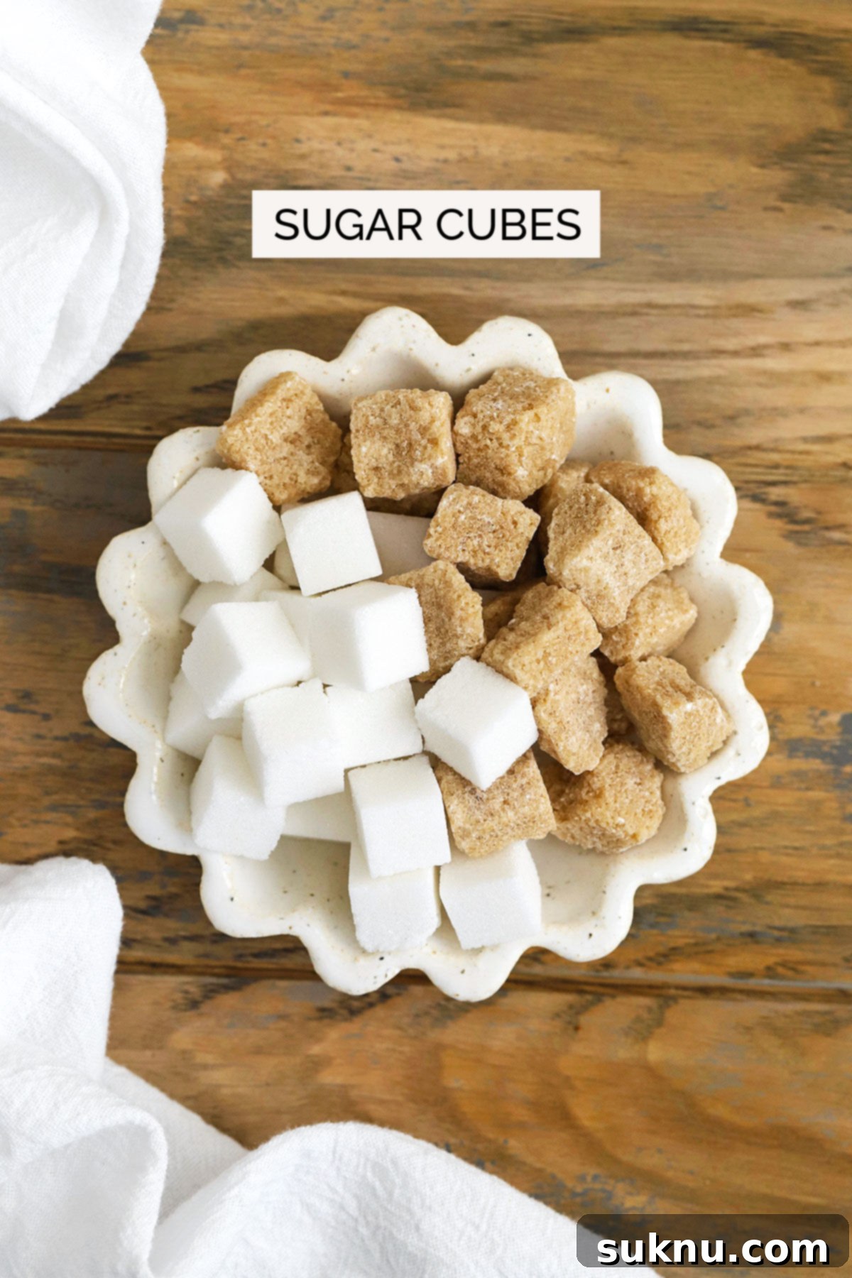 Mastering Sweetness: 12 Sugar Types and Their Culinary Applications 14 sugar cubes in a ruffled white bowl