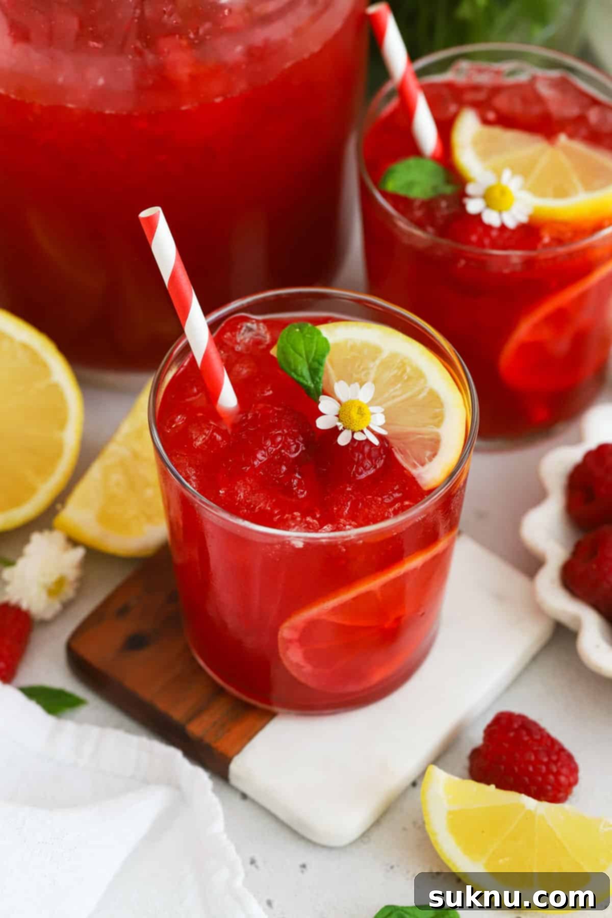 Perfect Raspberry Lemonade 2 glasses of fresh raspberry lemonade garnished with mint and lemon slices