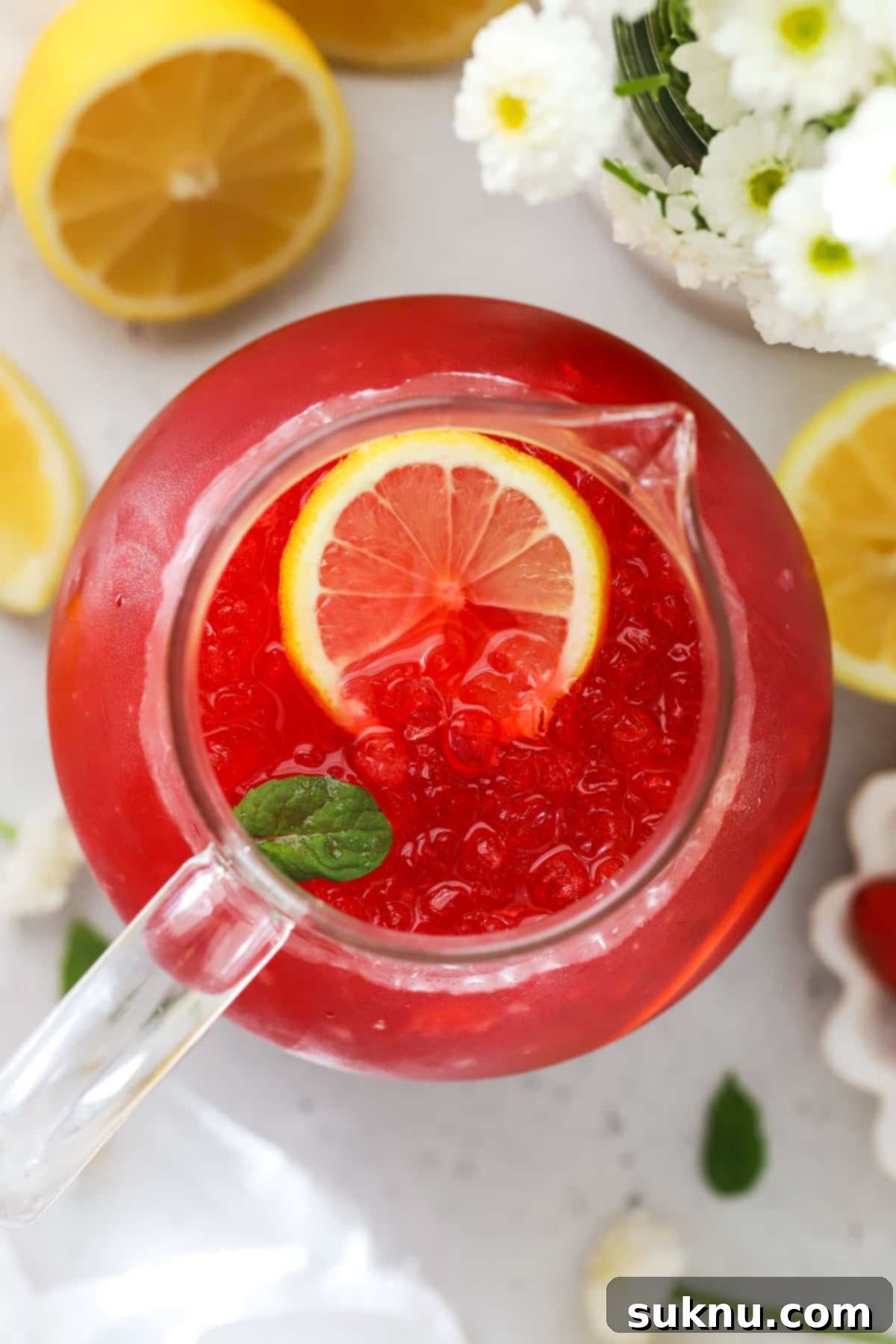 Perfect Raspberry Lemonade 5 a pitcher of homemade raspberry lemonade next to fresh flowers and lemnons, ready to be served
