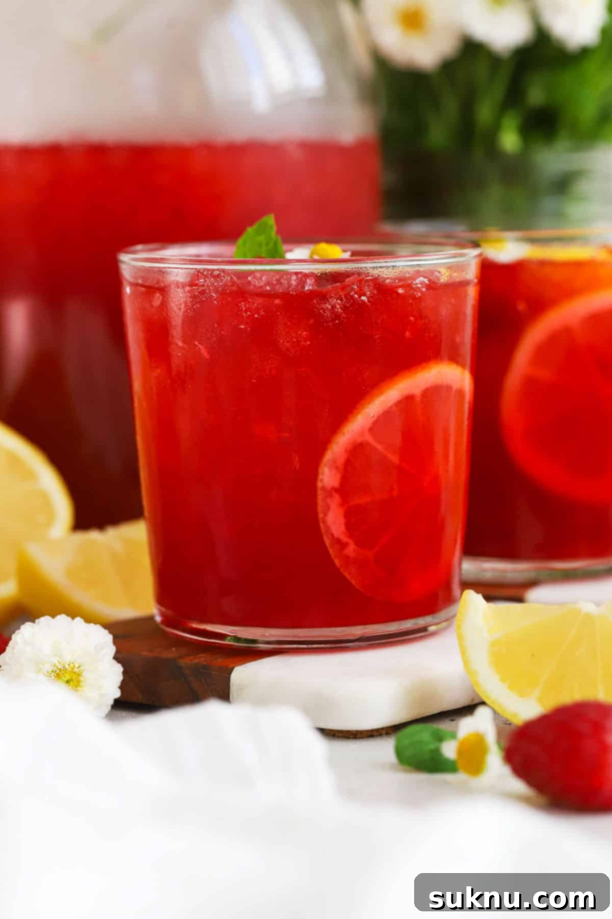 Perfect Raspberry Lemonade 7 glasses of bright pink raspberry lemonade garnished with fresh mint and lemon slices, ready to be enjoyed