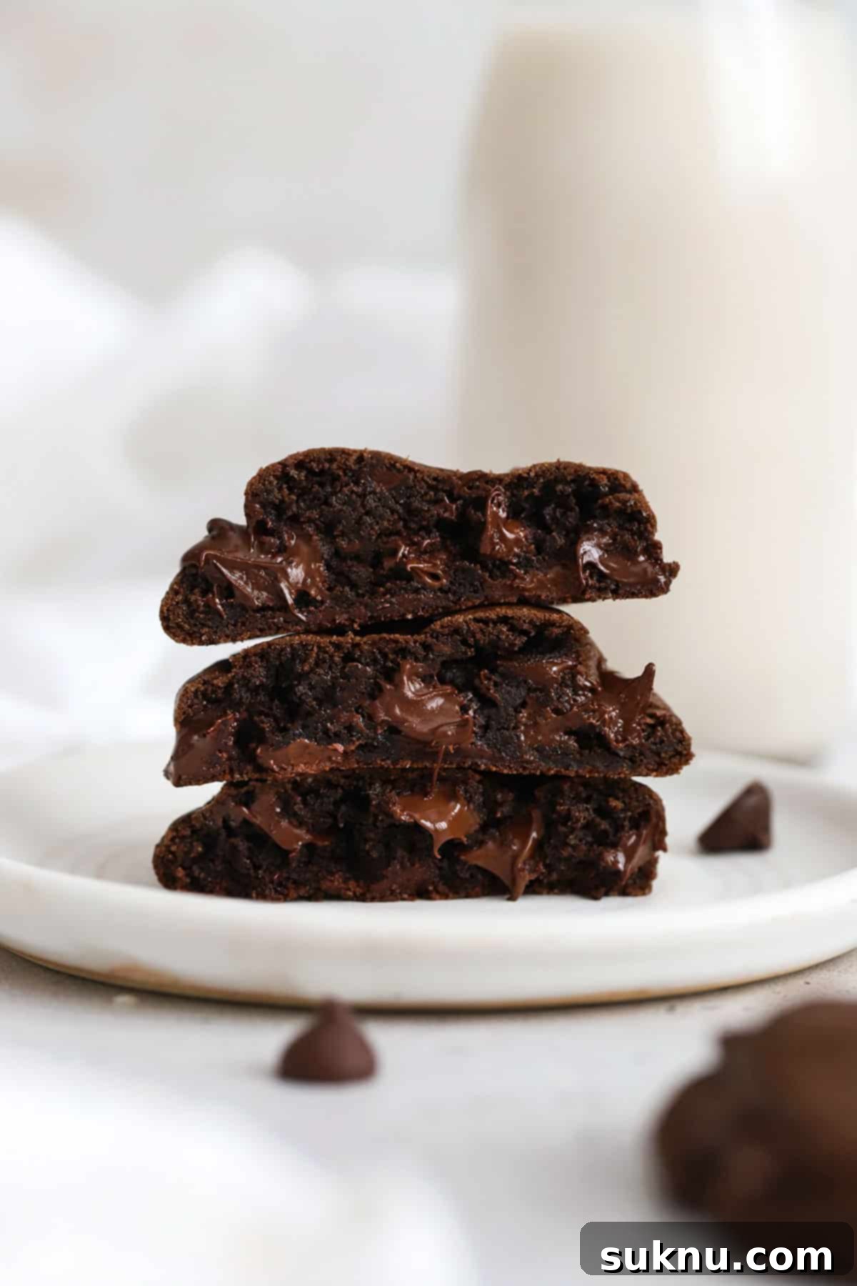 Gluten-Free Double Chocolate Chip Cookies 2 Three perfectly baked gluten-free double chocolate chip cookies stacked on a clean white plate, showcasing their rich color and melted chocolate chips.