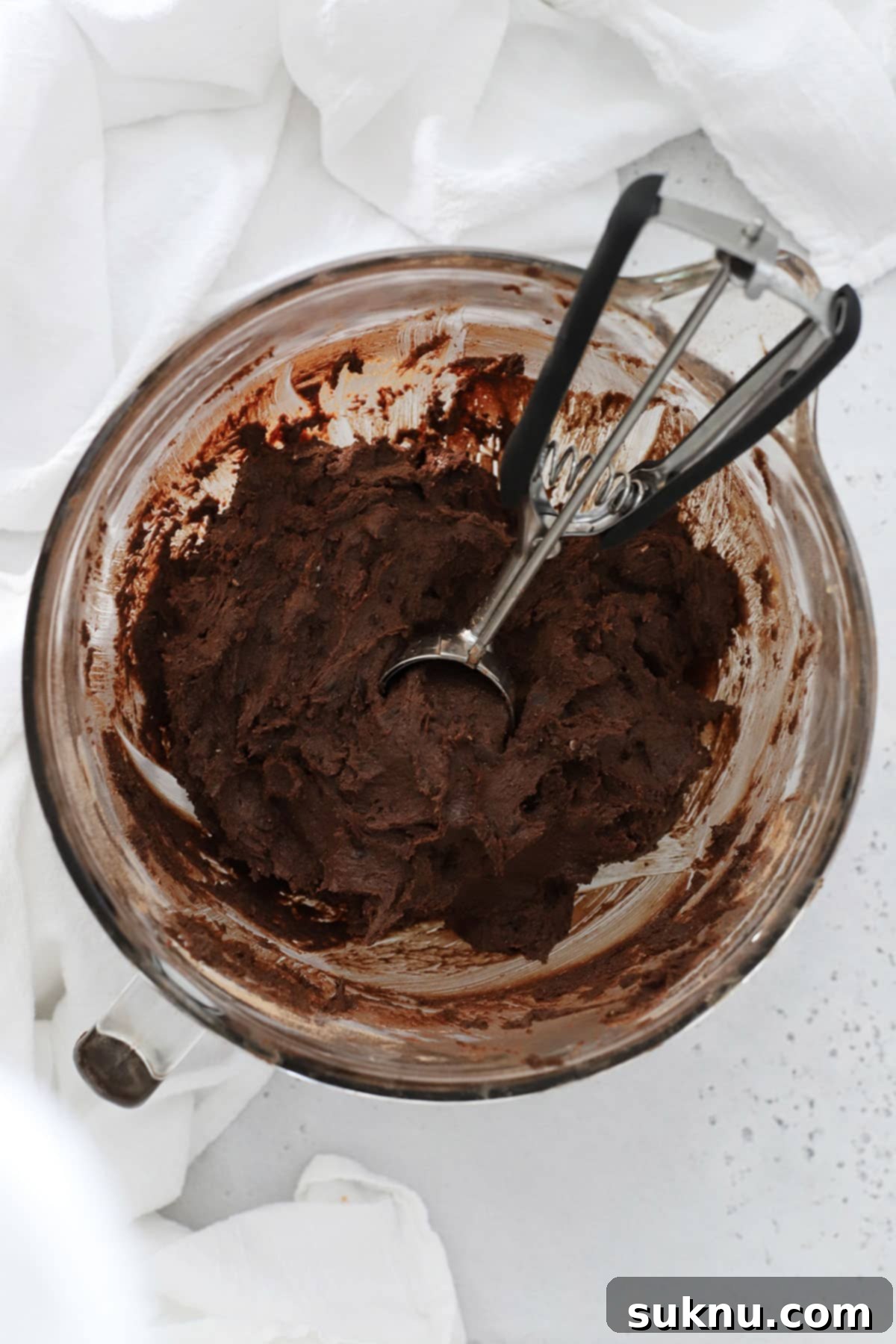 Gluten-Free Double Chocolate Chip Cookies 4 Gluten-free chocolate cookie dough in a mixing bowl, showcasing its rich, dark color and thick consistency, ready for baking.