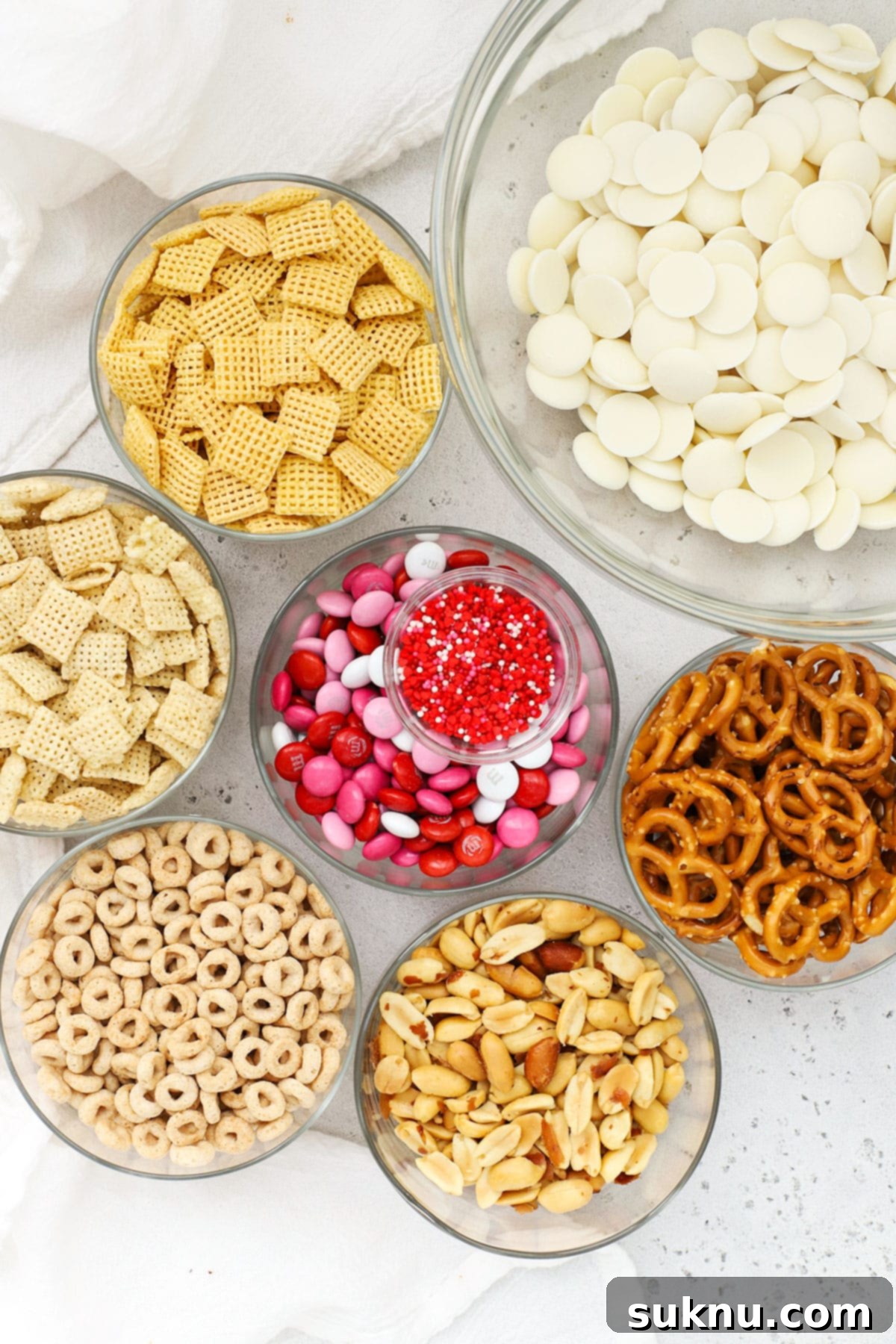 Collection of ingredients for gluten-free Valentines Chex Mix including cereals, pretzels, M&Ms, and chocolate melts