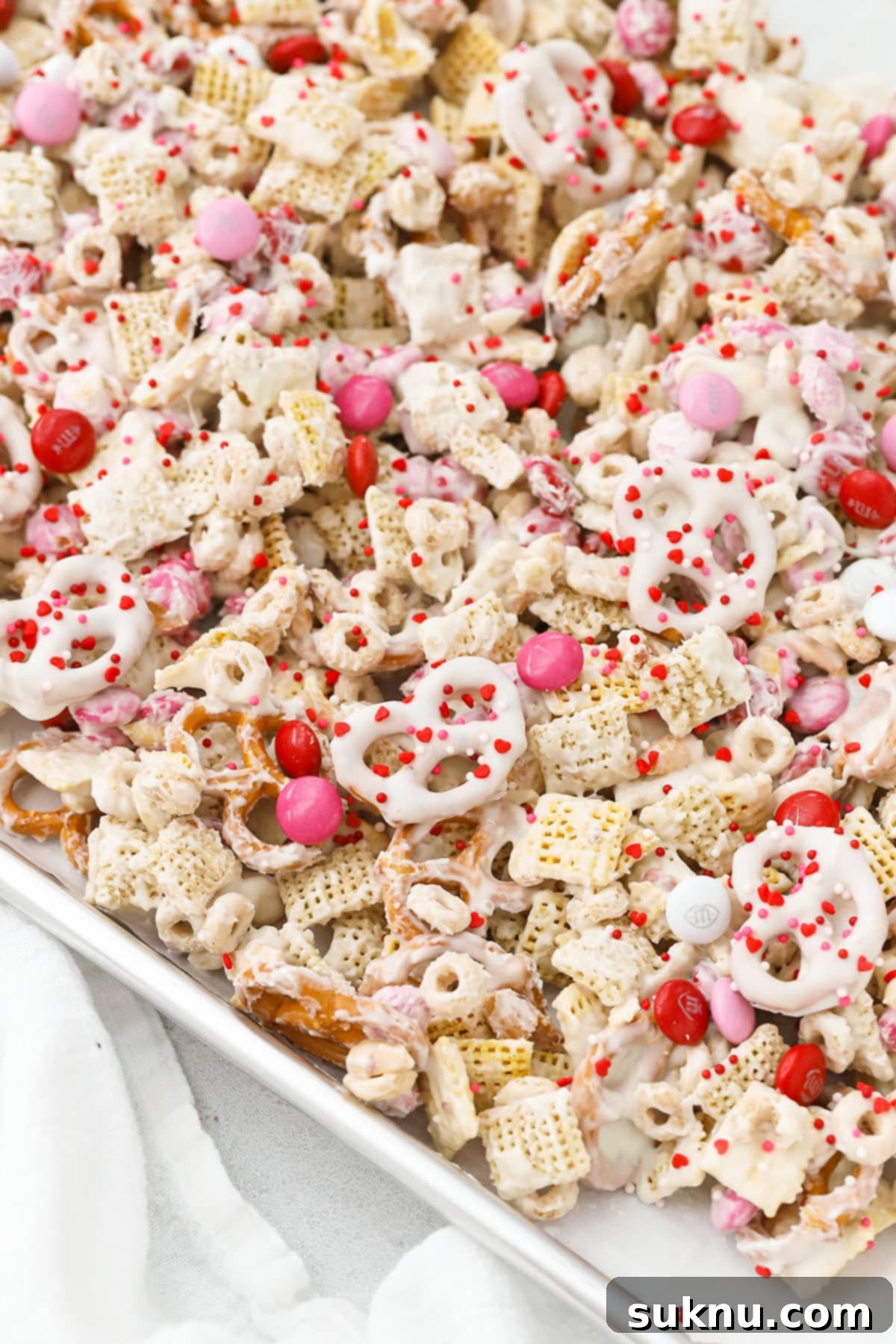 Spreading Valentine's snack mix on a baking sheet to cool and set
