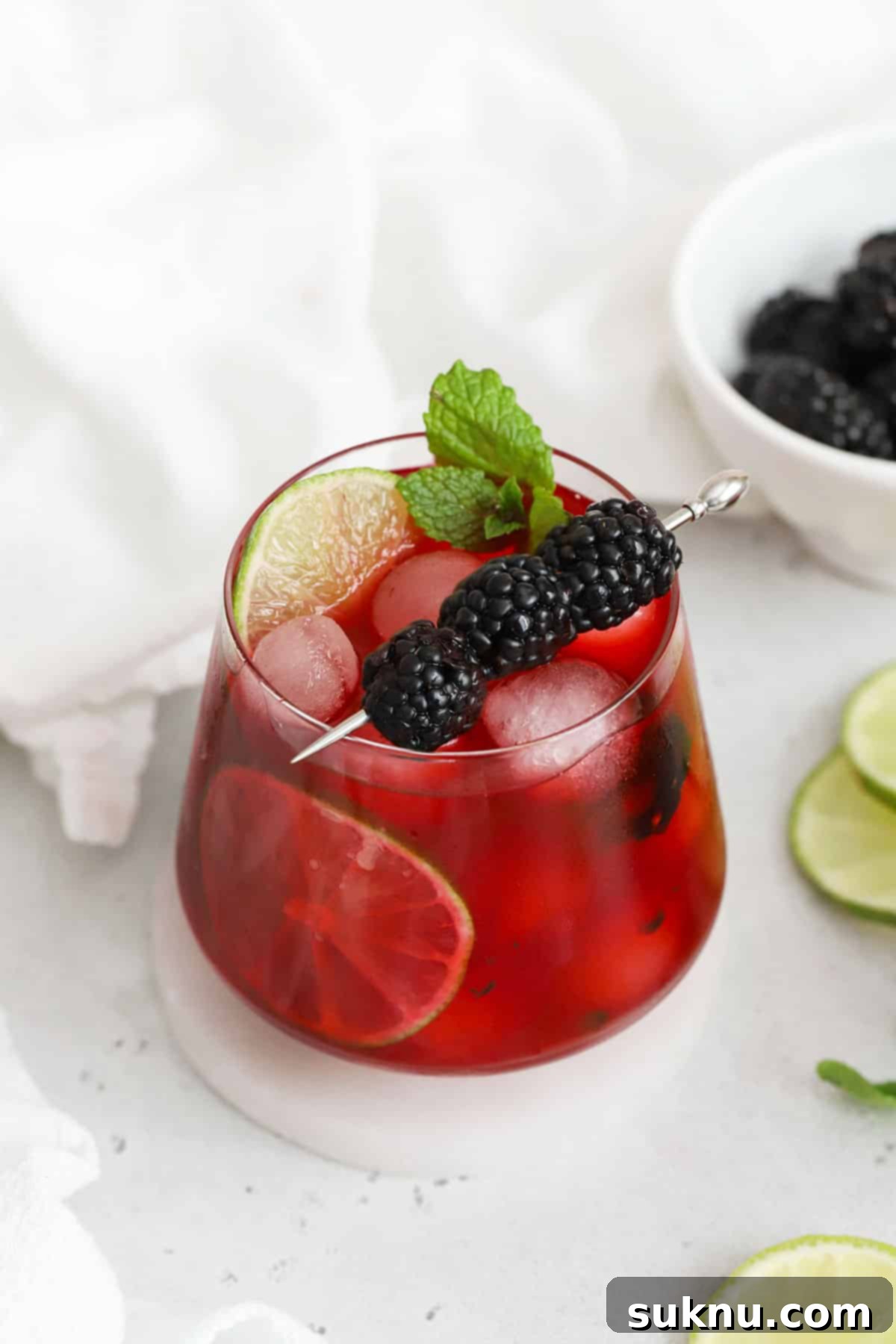 A short glass of homemade blackberry limeade, garnished with fresh mint leaves and whole blackberries, ready to be enjoyed.