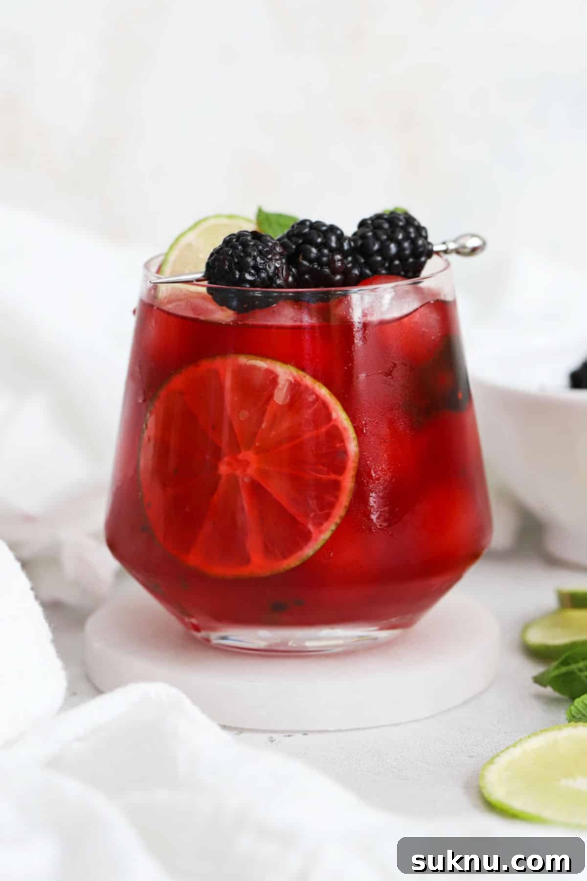 Short glass of blackberry limeade garnished with fresh mint and blackberries, with a bright, inviting appearance.