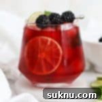 short glass of blackberry limeade garnished with fresh mint and blackberries