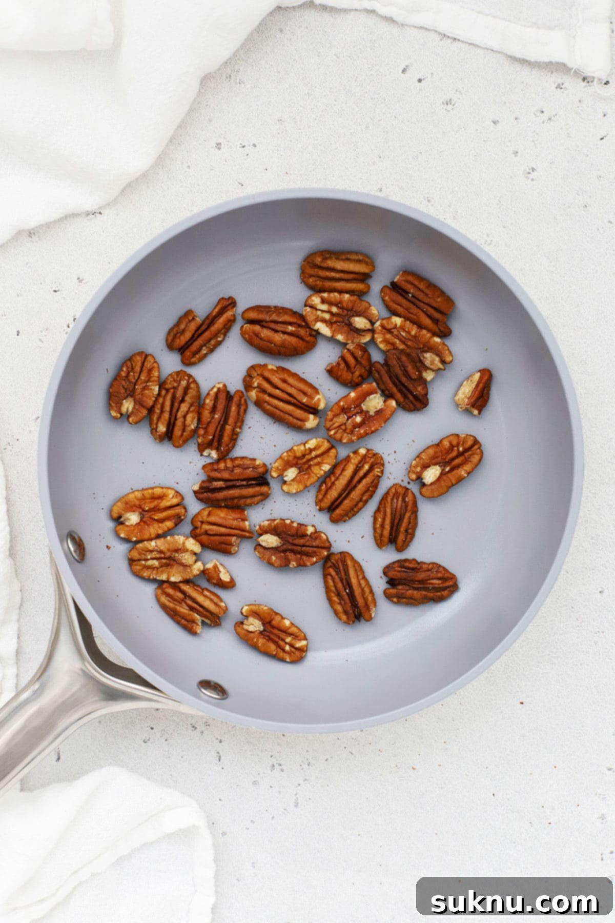 Toasting pecans in a pan on the stove, showing constant stirring for even browning