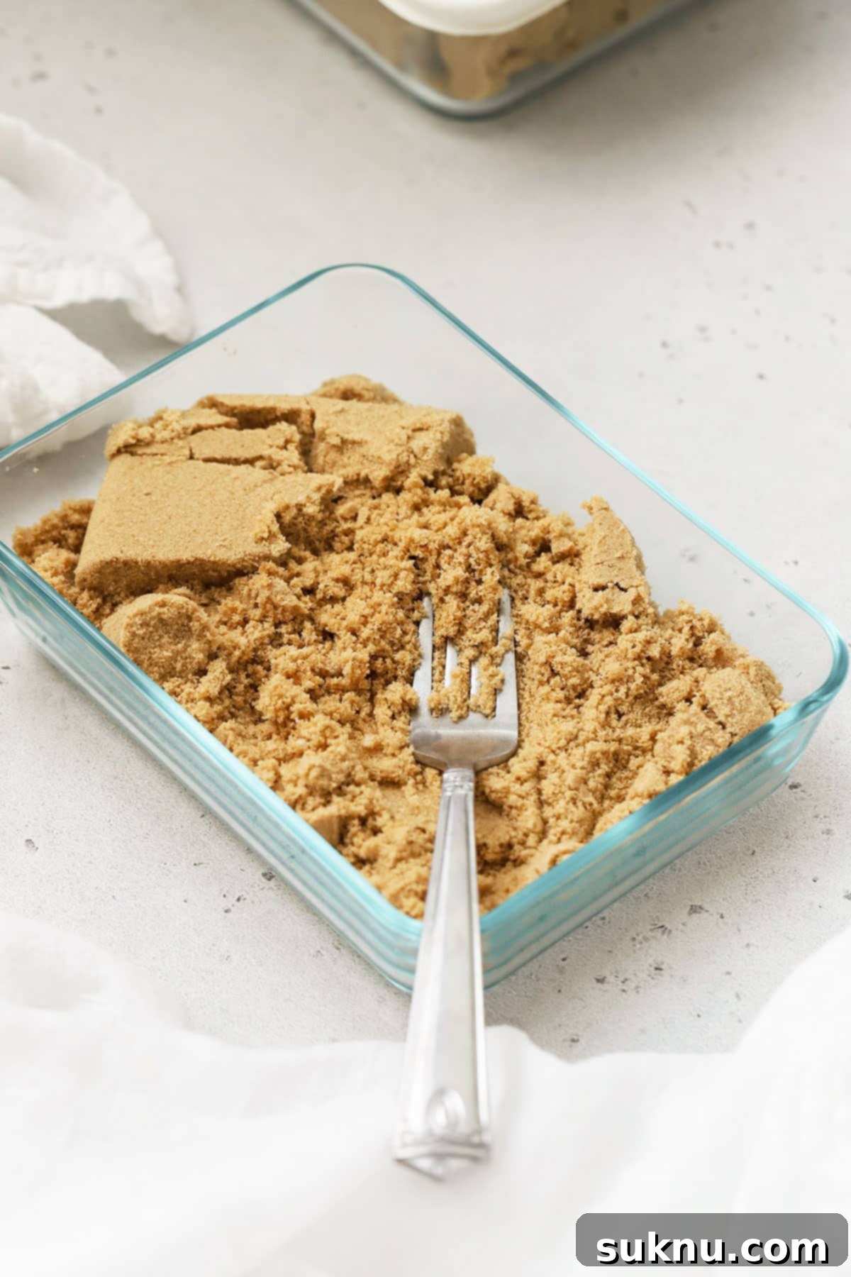 Revive Your Hard Brown Sugar 5 A shallow rectangular baking dish filled with softened brown sugar, showcasing its loose and pliable texture.