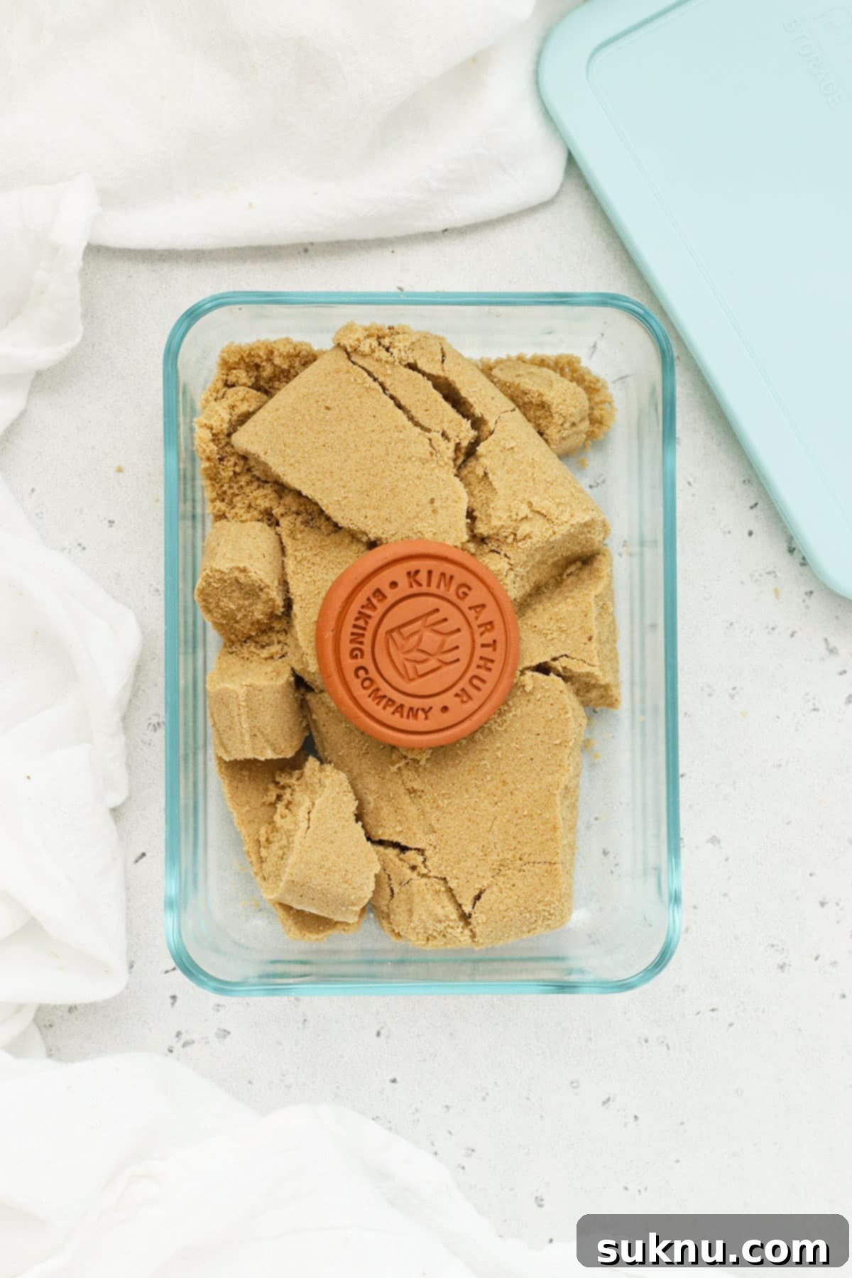 Revive Your Hard Brown Sugar 8 A terra cotta disc resting on top of brown sugar in a container, illustrating its use as a sugar saver.