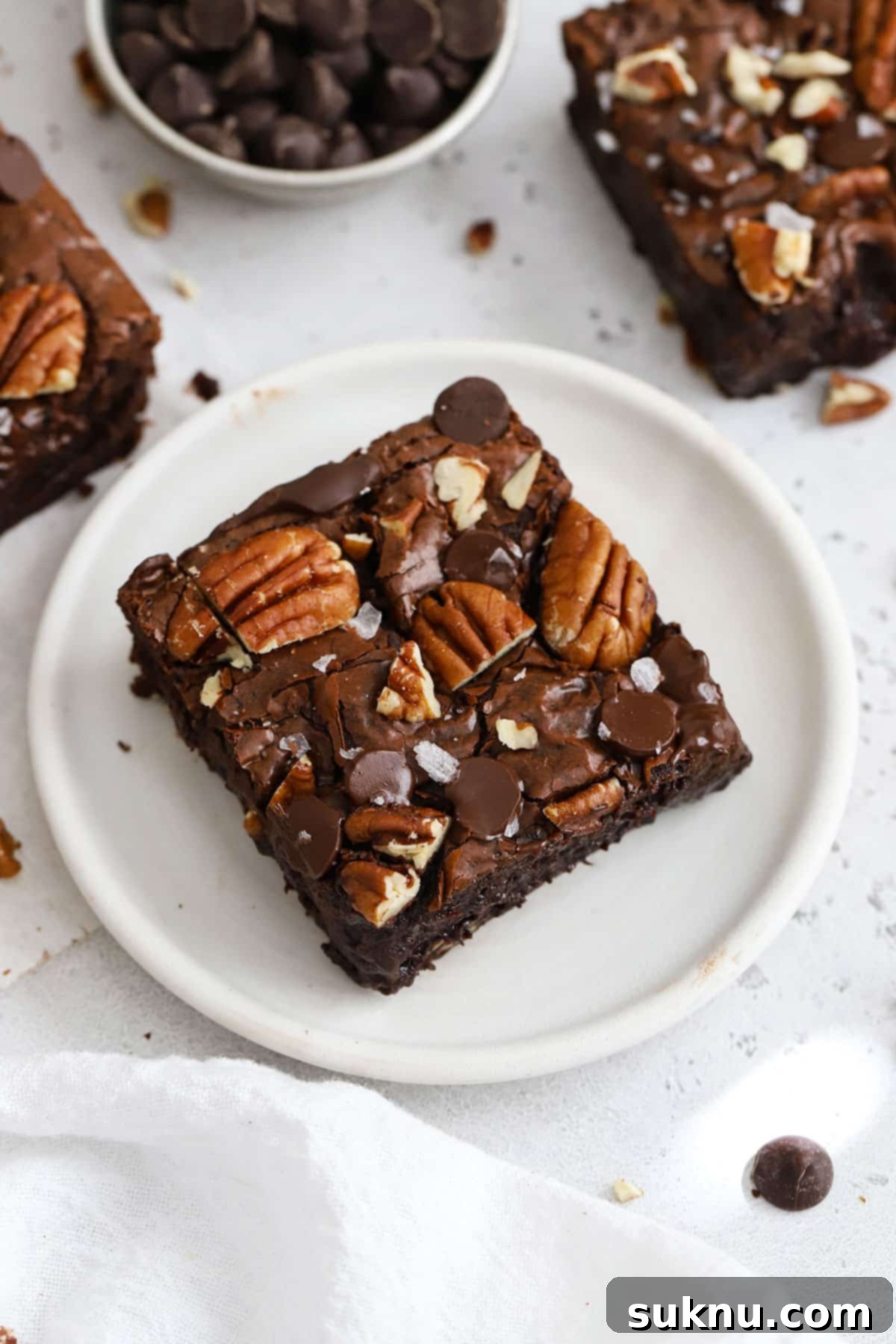 Decadent Gluten-Free Pecan Brownies 13 A single fudgy gluten-free pecan brownie presented on a pristine white plate, showcasing its glossy top and crunchy pecan pieces.