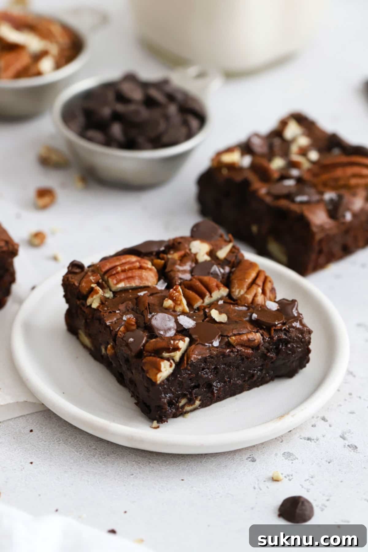 Decadent Gluten-Free Pecan Brownies 6 A close-up of a single gluten-free pecan brownie on a white plate, highlighting its rich texture and pecan toppings.