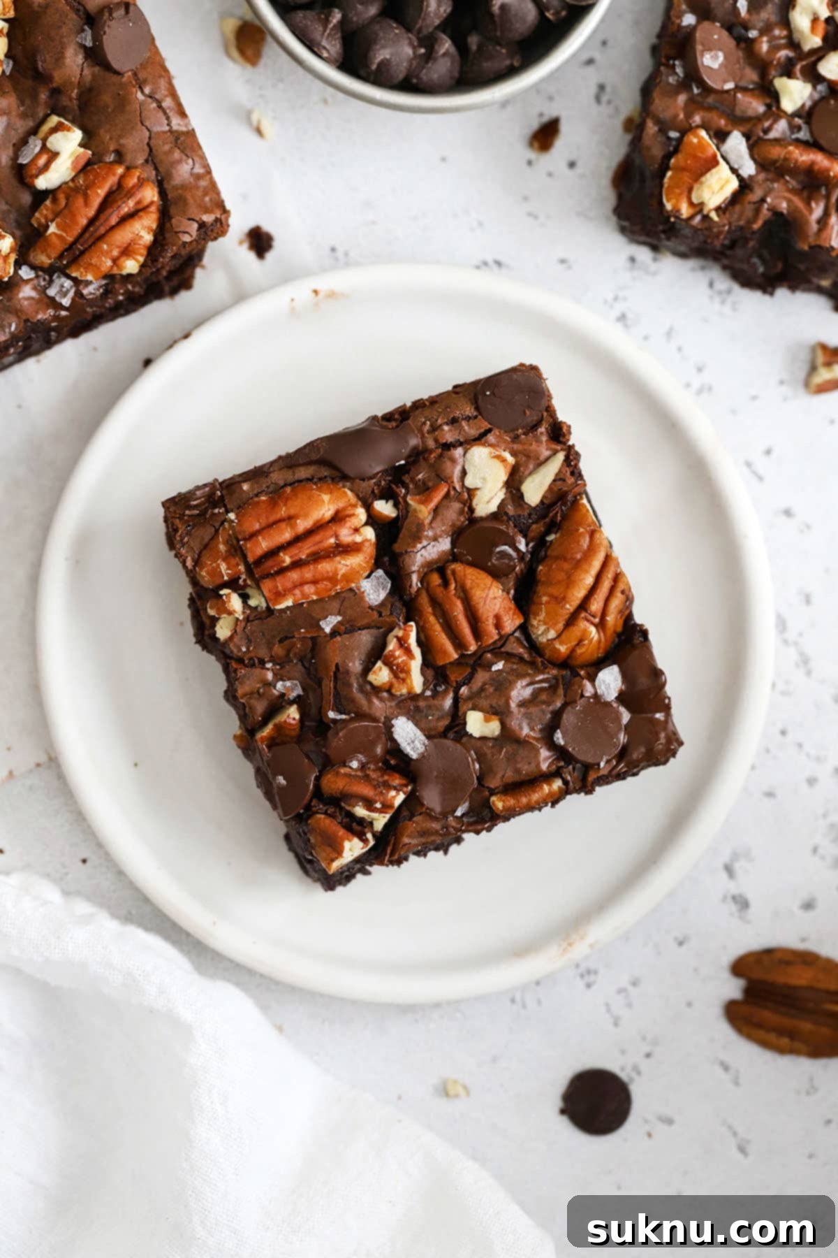 Decadent Gluten-Free Pecan Brownies 8 A single fudgy gluten-free pecan brownie on a white plate, ready to be enjoyed.