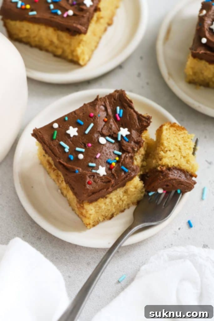 Zesty Gluten-Free Lemon Bundt Cake 11 A slice of fluffy gluten-free yellow sheet cake on a white dessert plate with chocolate frosting.