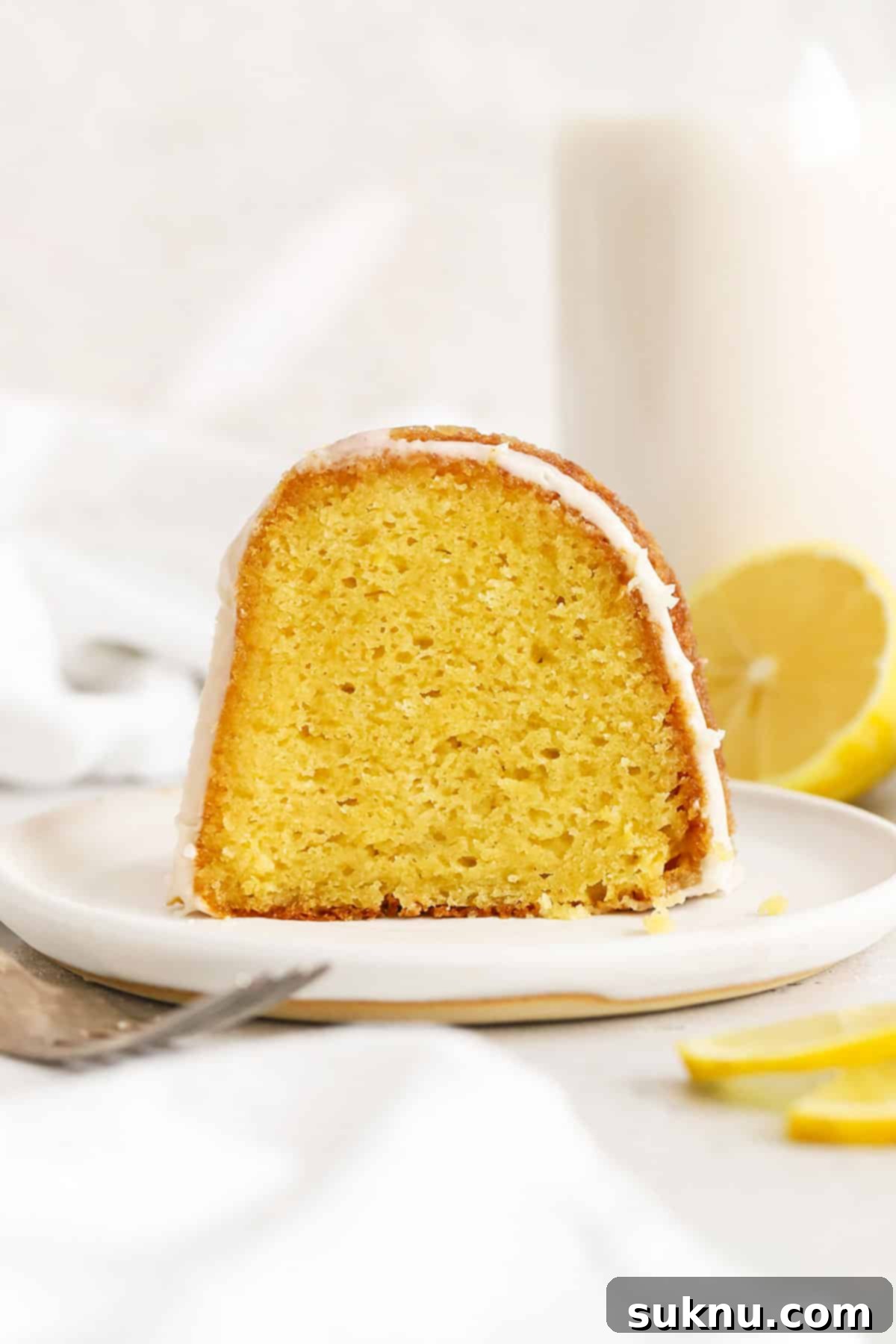 Zesty Gluten-Free Lemon Bundt Cake 8 A perfectly sliced piece of gluten-free lemon bundt cake on a white plate, highlighting its moist crumb.