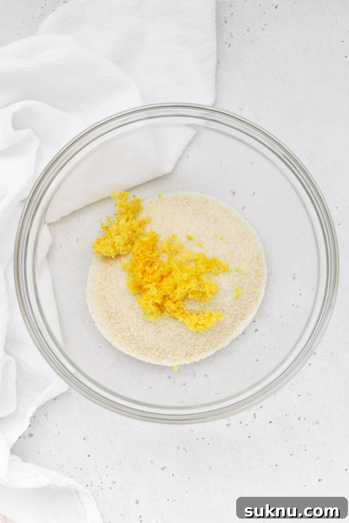 Lemon zest on top of sugar in a glass bowl, illustrating its texture and appearance