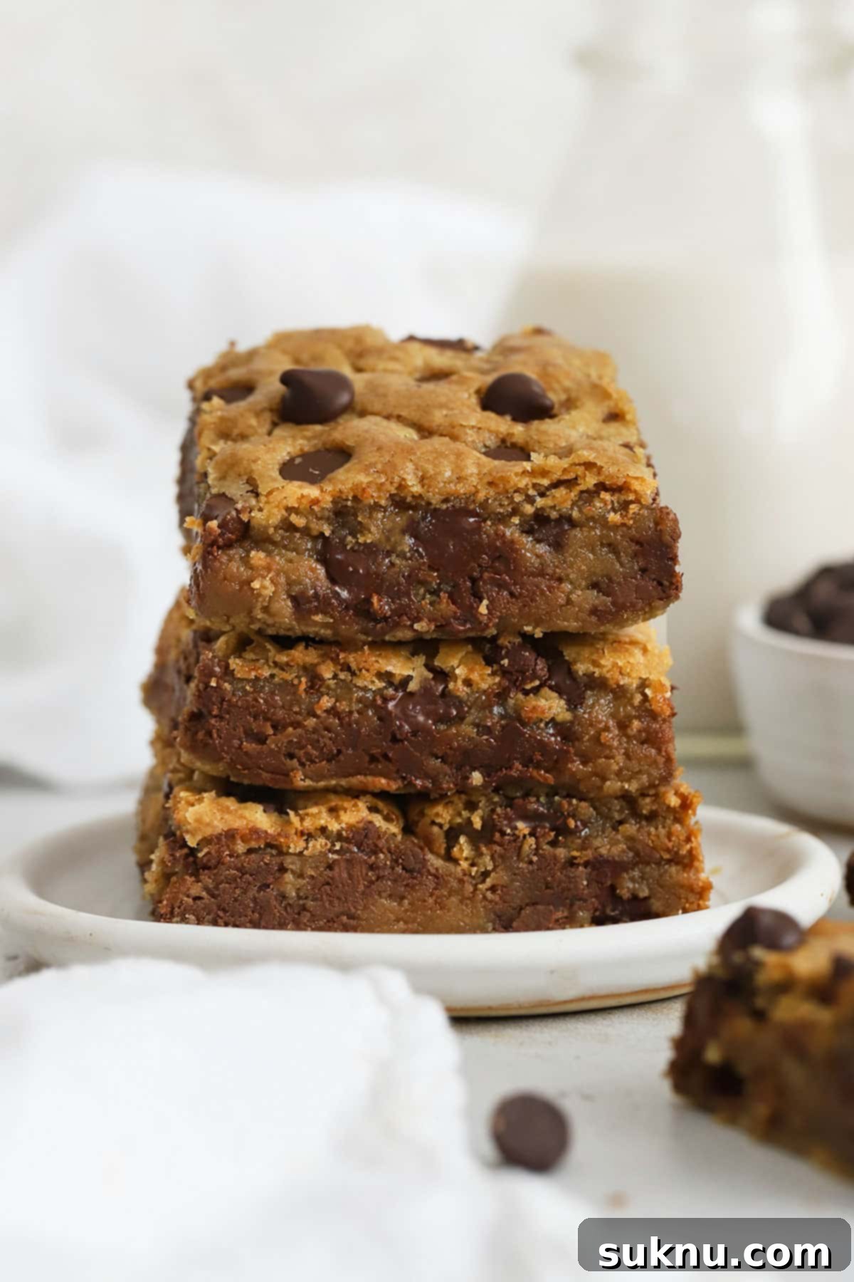 Ultimate Gluten-Free Chocolate Chip Cookie Bars 7 A stack of perfectly baked gluten-free chocolate chip blondie bars on a white plate, invitingly arranged.