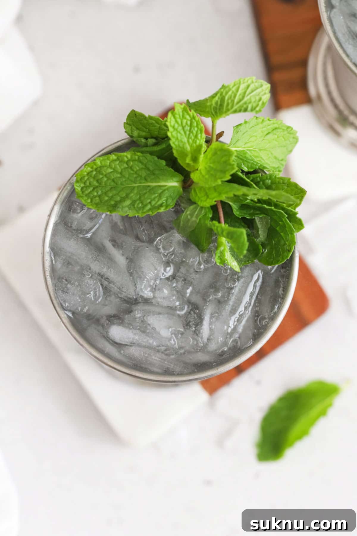 Disneyland Style Mint Julep 6 Two Virgin Mint Julep mocktails sit in frosty metal julep cups, garnished with fresh mint, casting a refreshing glow. The background is softly blurred, keeping the focus on the inviting beverages.