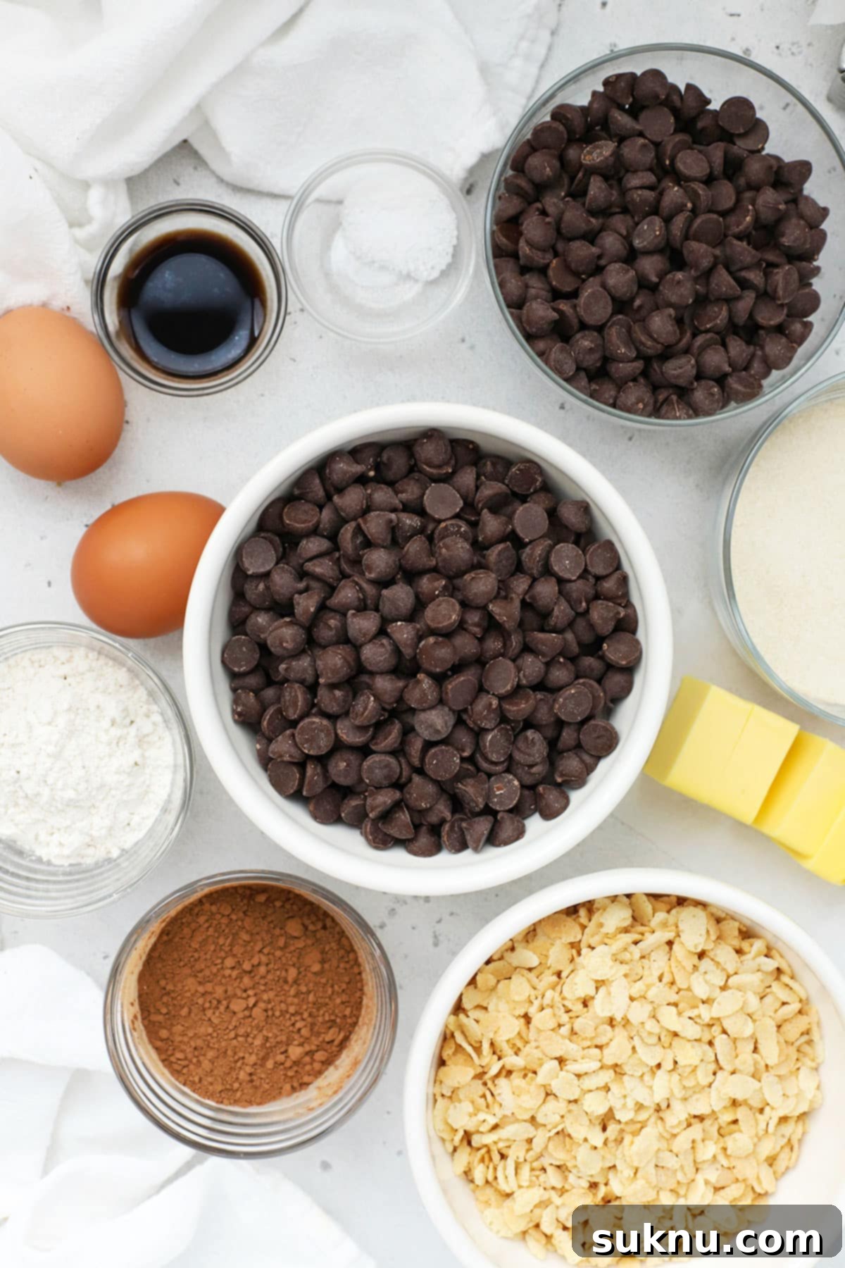 Gluten Free Crunchy Brownies 3 Ingredients laid out on a table for making gluten-free crunch bar brownies, including chocolate chips, butter, eggs, flour, and crisp rice cereal.