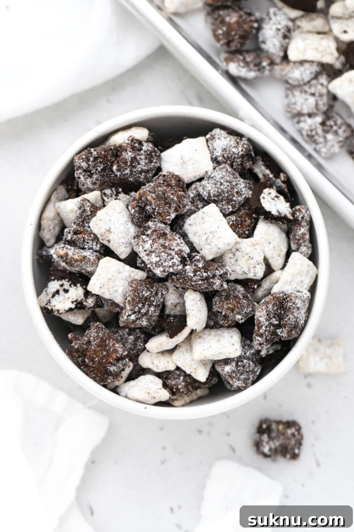 A delectable bowl of cookies and cream muddy buddies, adorned with generous pieces of chopped gluten-free Oreos.