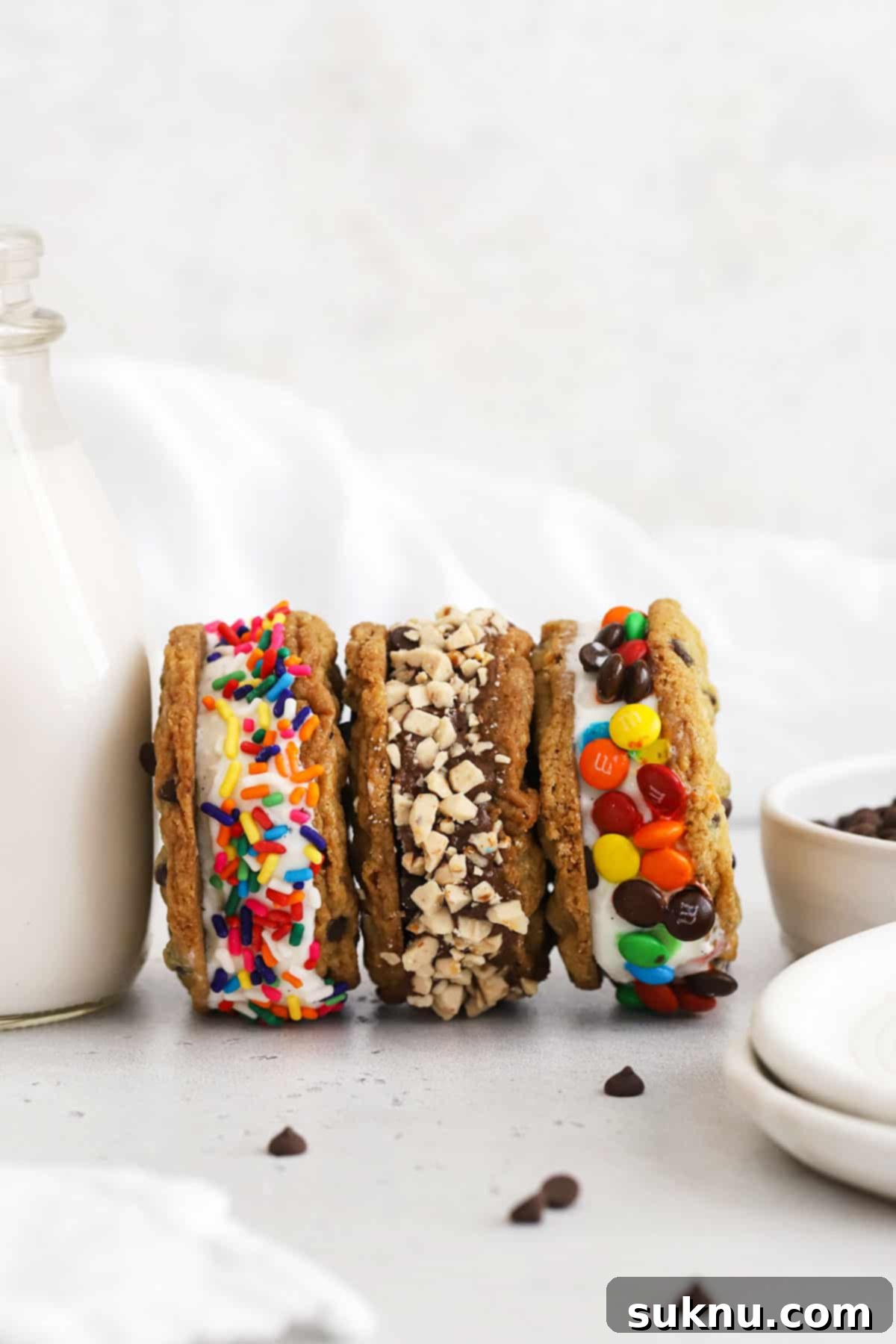 Gluten-free cookie ice cream sandwiches with various fun toppings rolled on their sides, ready to be enjoyed.